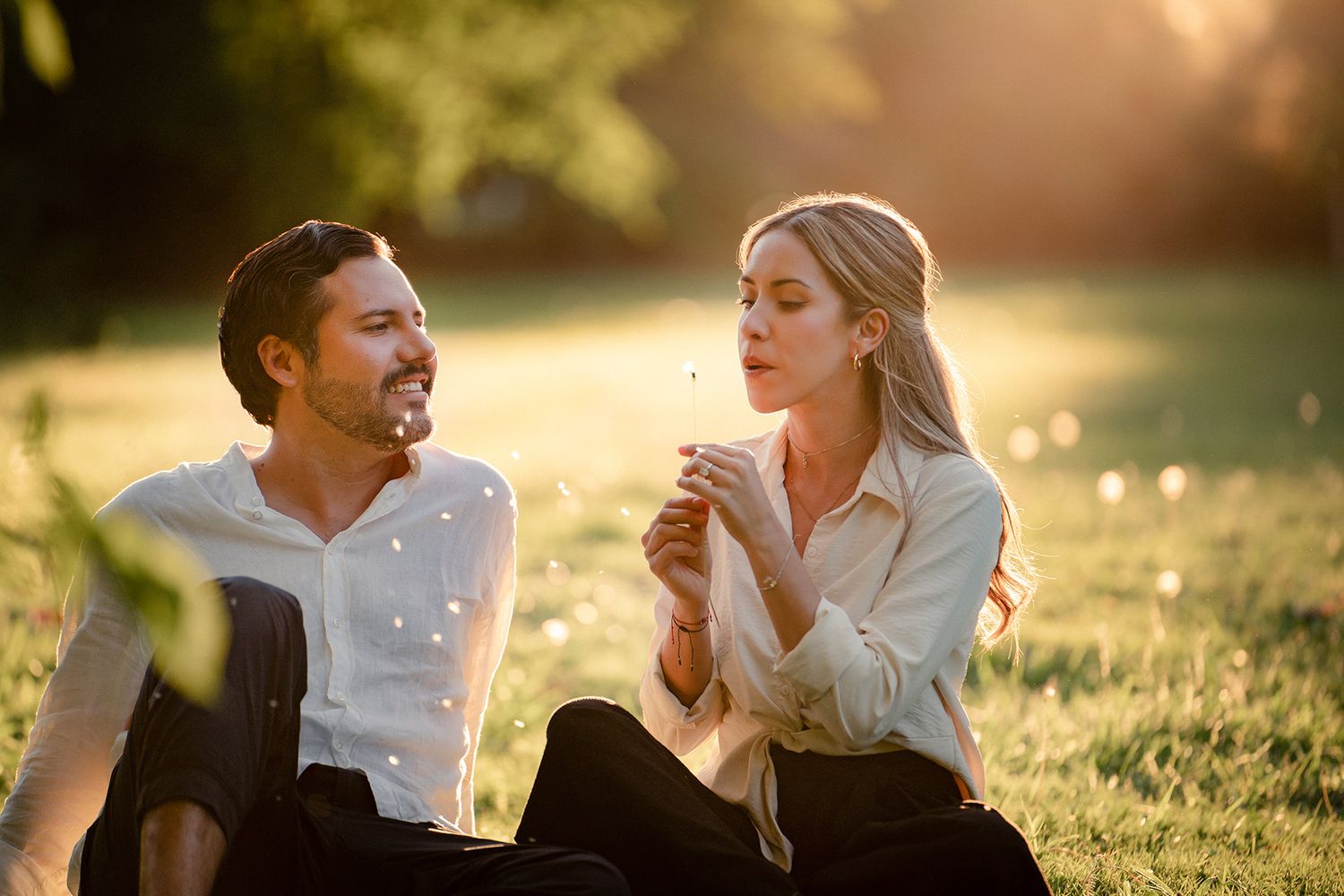 A couple enjoys a playful moment together in a sunlit field at golden hour.