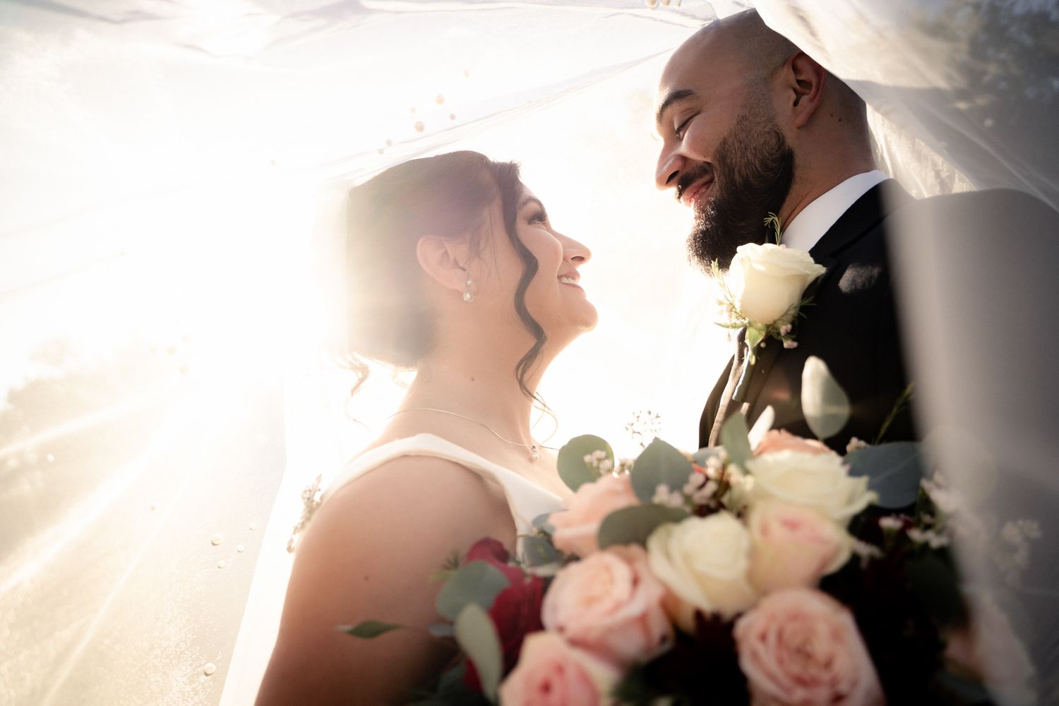 Romantic backlit silhouette of newlyweds with bouquet of roses.