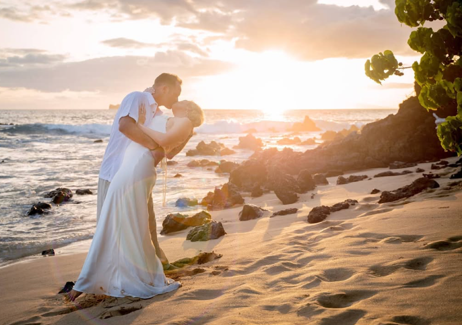 Intimate moment between couple on sandy beach during golden hour sunset.