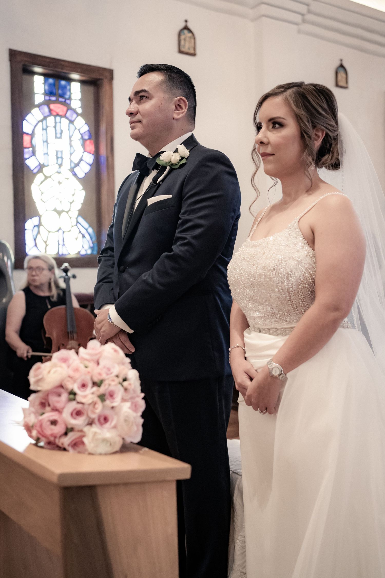Wedding couple stands at decorated church altar during traditional ceremony.