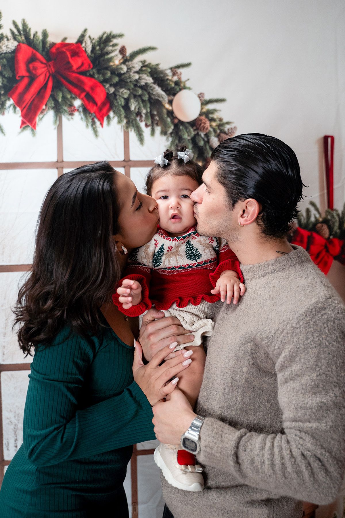 A sweet family moment captured during a Christmas photo session with red bows and decorative elements.