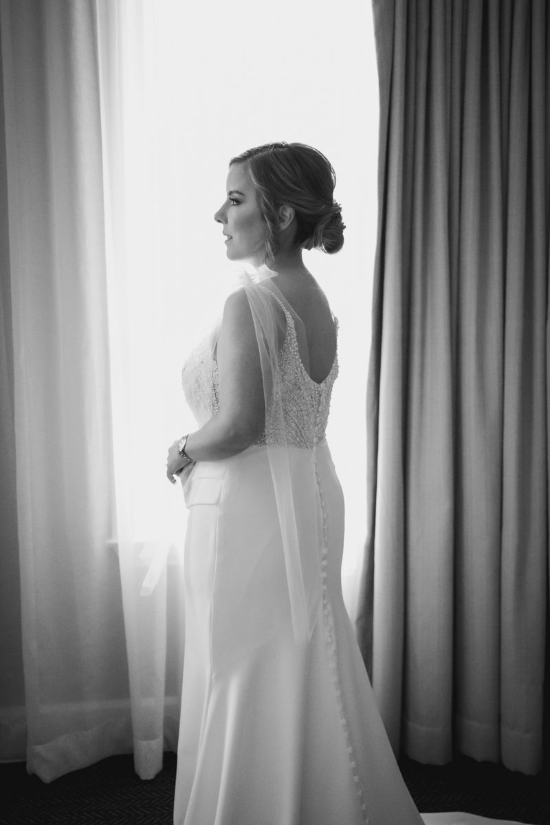 Elegant bridal portrait showing intricate lace details of a classic wedding gown in black and white.