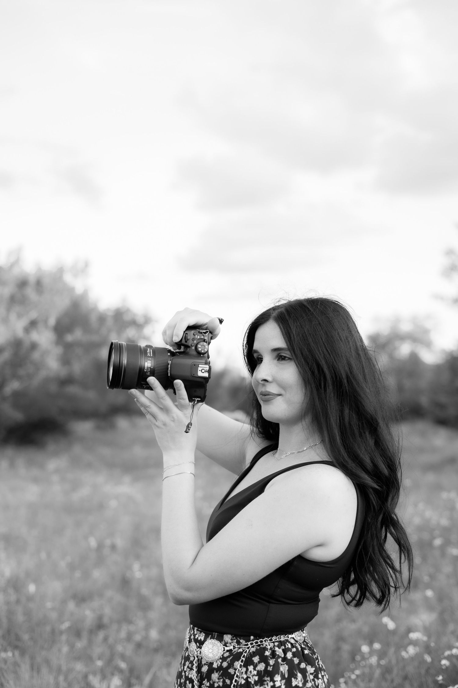 Black and white photos of photographer taking pictures with professional camera in field.