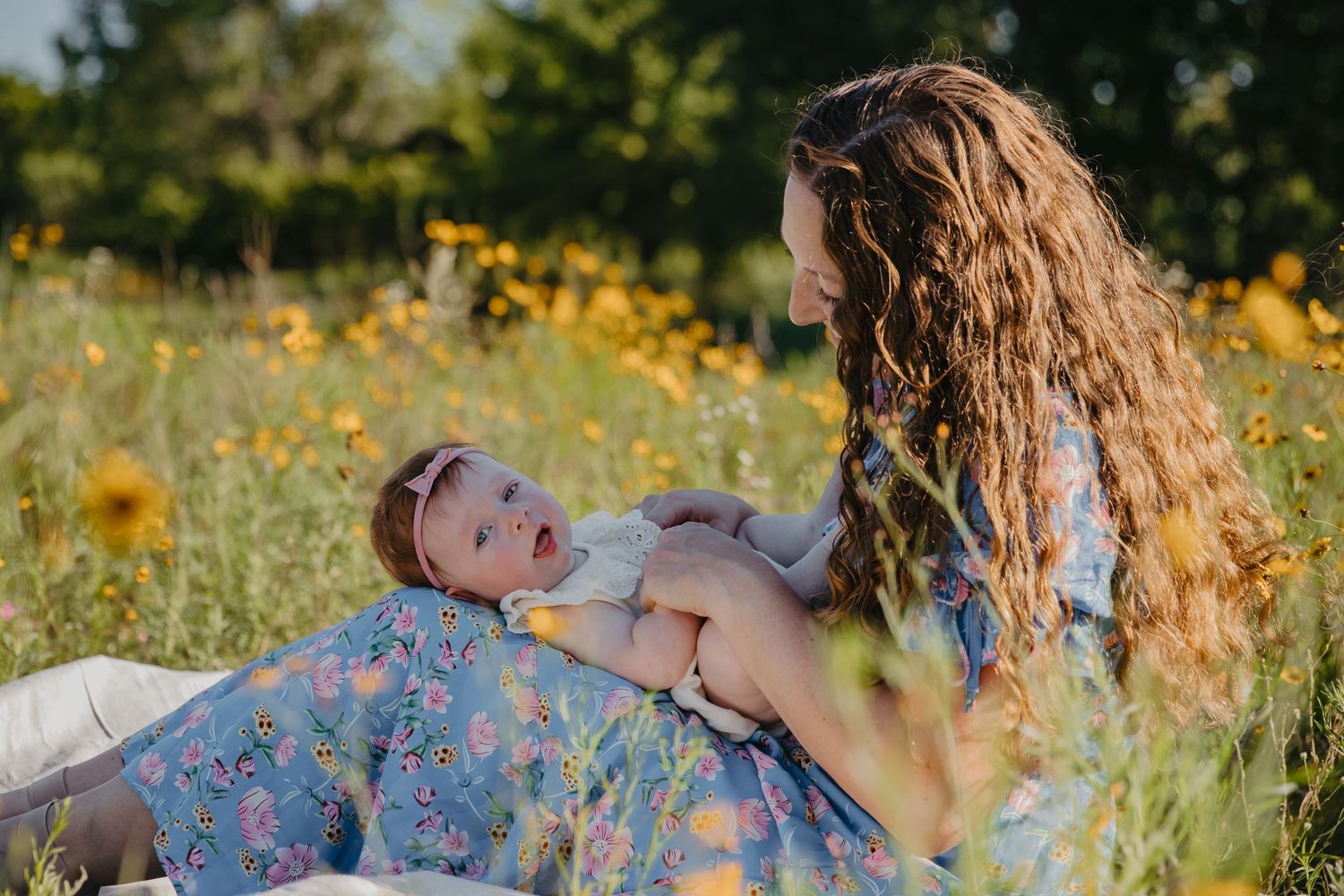 A joyful moment captured between parent and baby lying in a wildflower meadow on a sunny day.