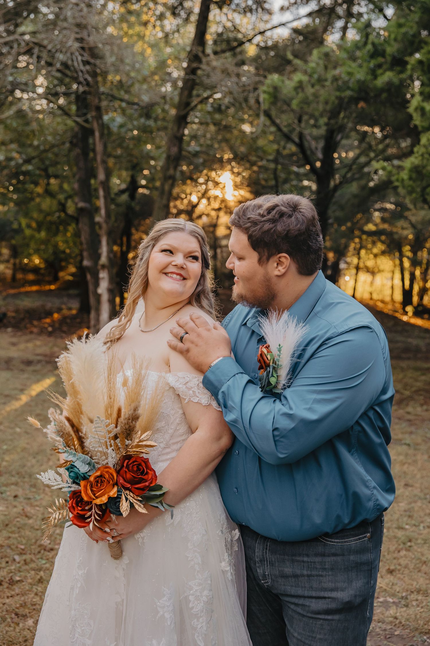 A couple shares a joyful moment in an autumn forest setting during their wedding photoshoot.