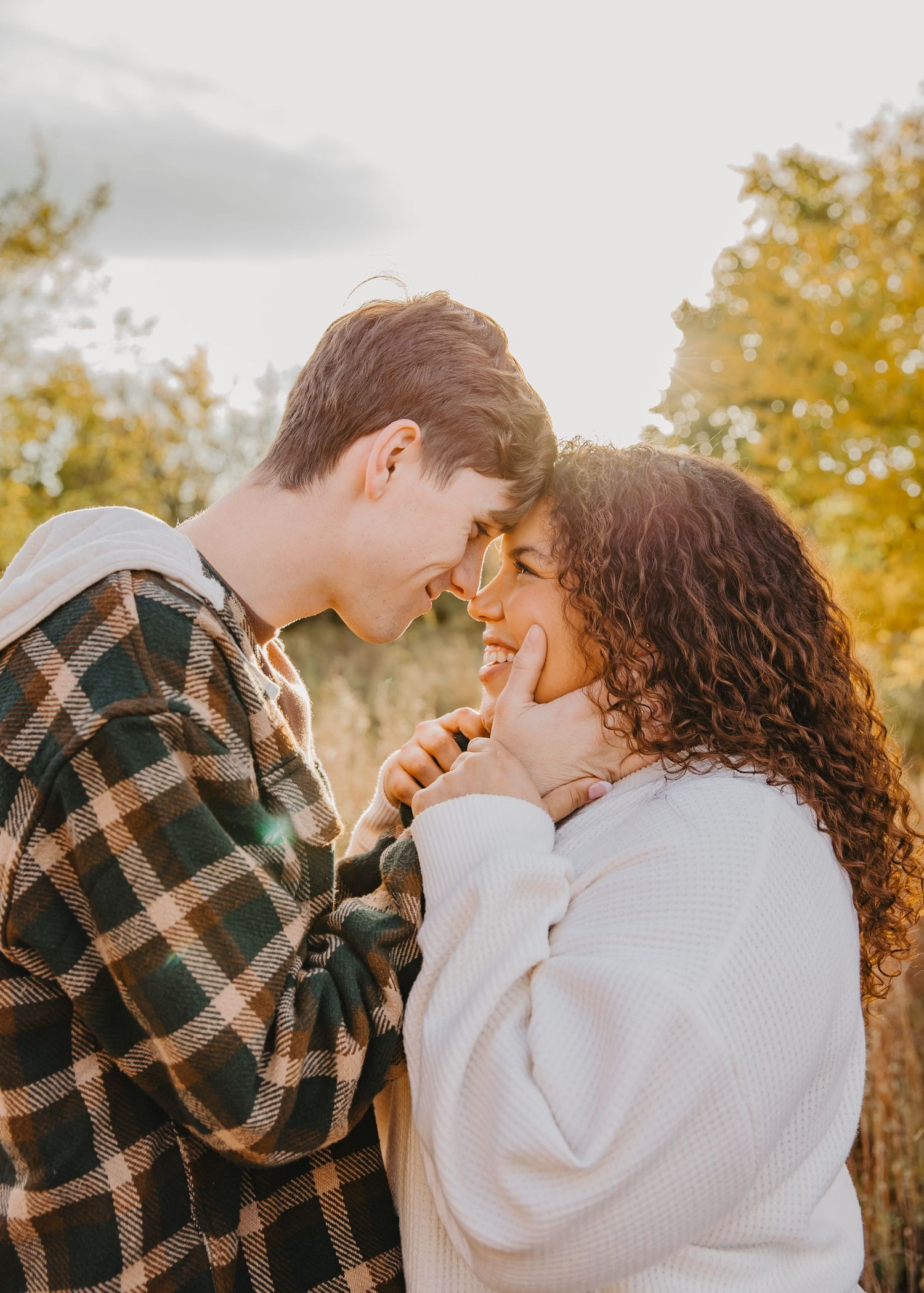A couple shares intimate moments in a series of romantic autumn photos with golden foliage in the background.