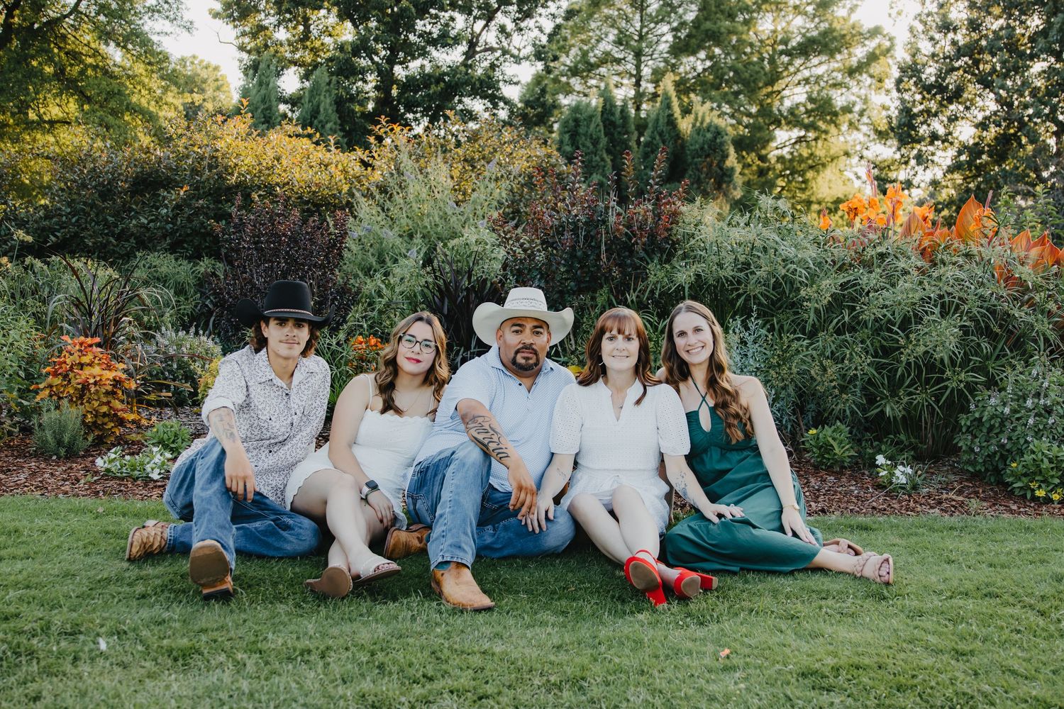 Group portrait in a garden setting with coordinated casual outfits against lush greenery.