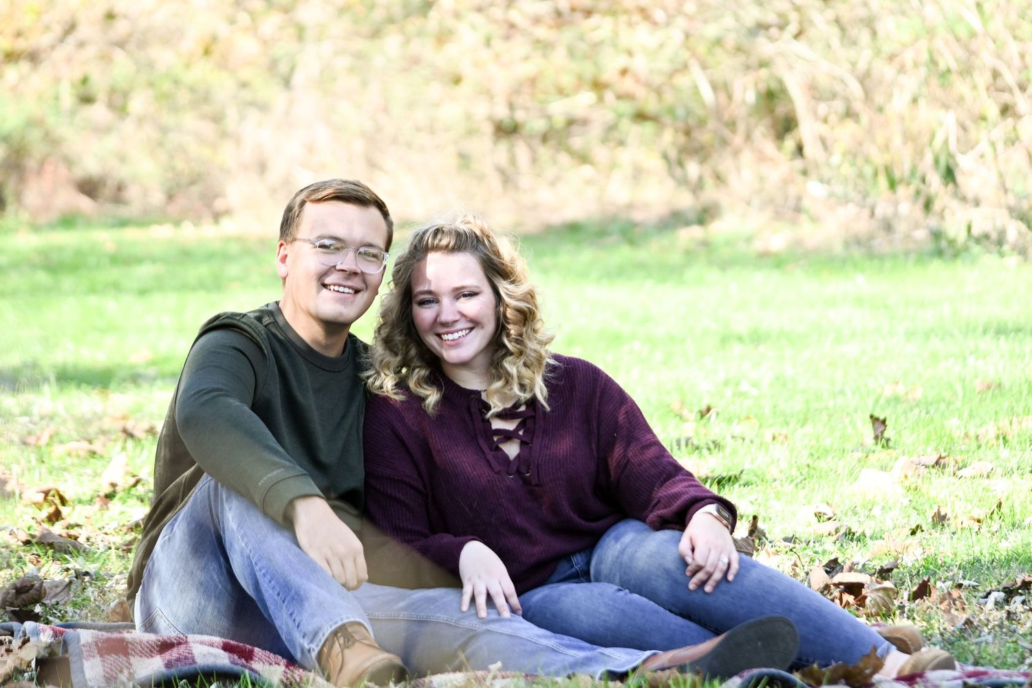 Cozy in the midst of fall, a young and in love couple are all smiles to celebrate their engagement.
