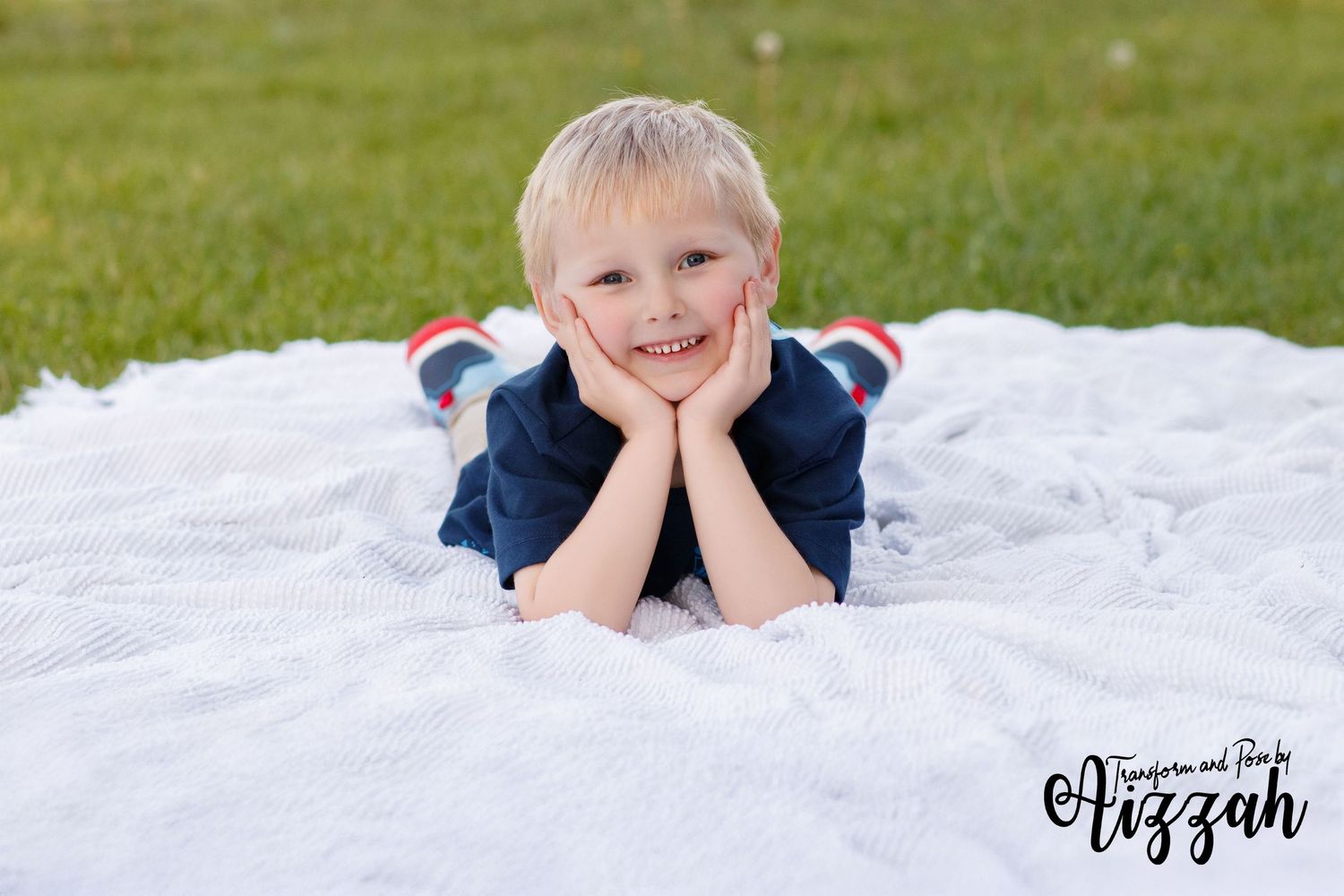 Young child lying on white blanket outdoors during photo session.
