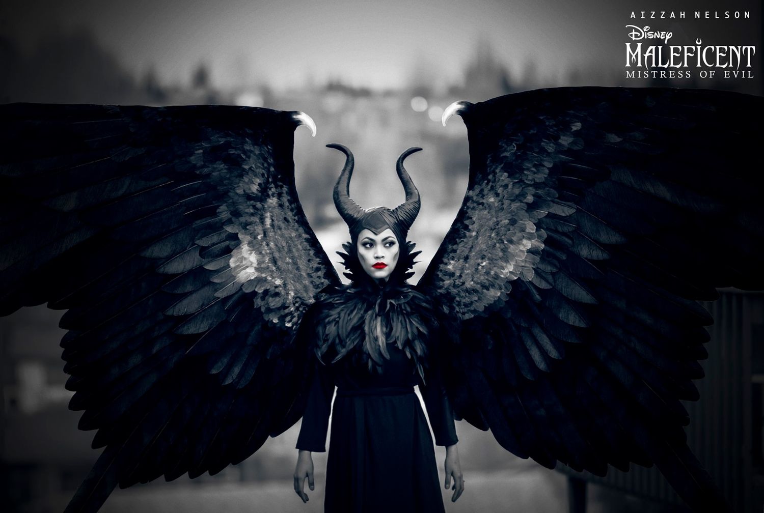 Dark atmospheric cosplay photo of Maleficent with large black wings against moody background.