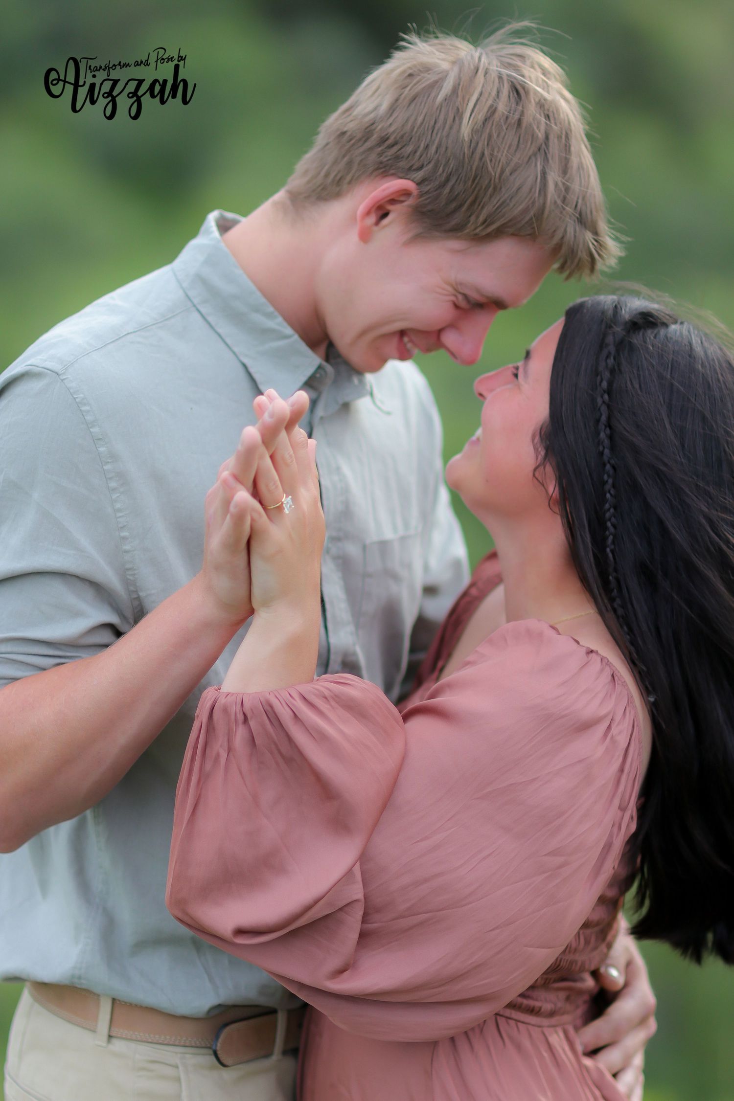 Romantic couple in grey and pink outfits share an intimate moment outdoors with clasped hands.