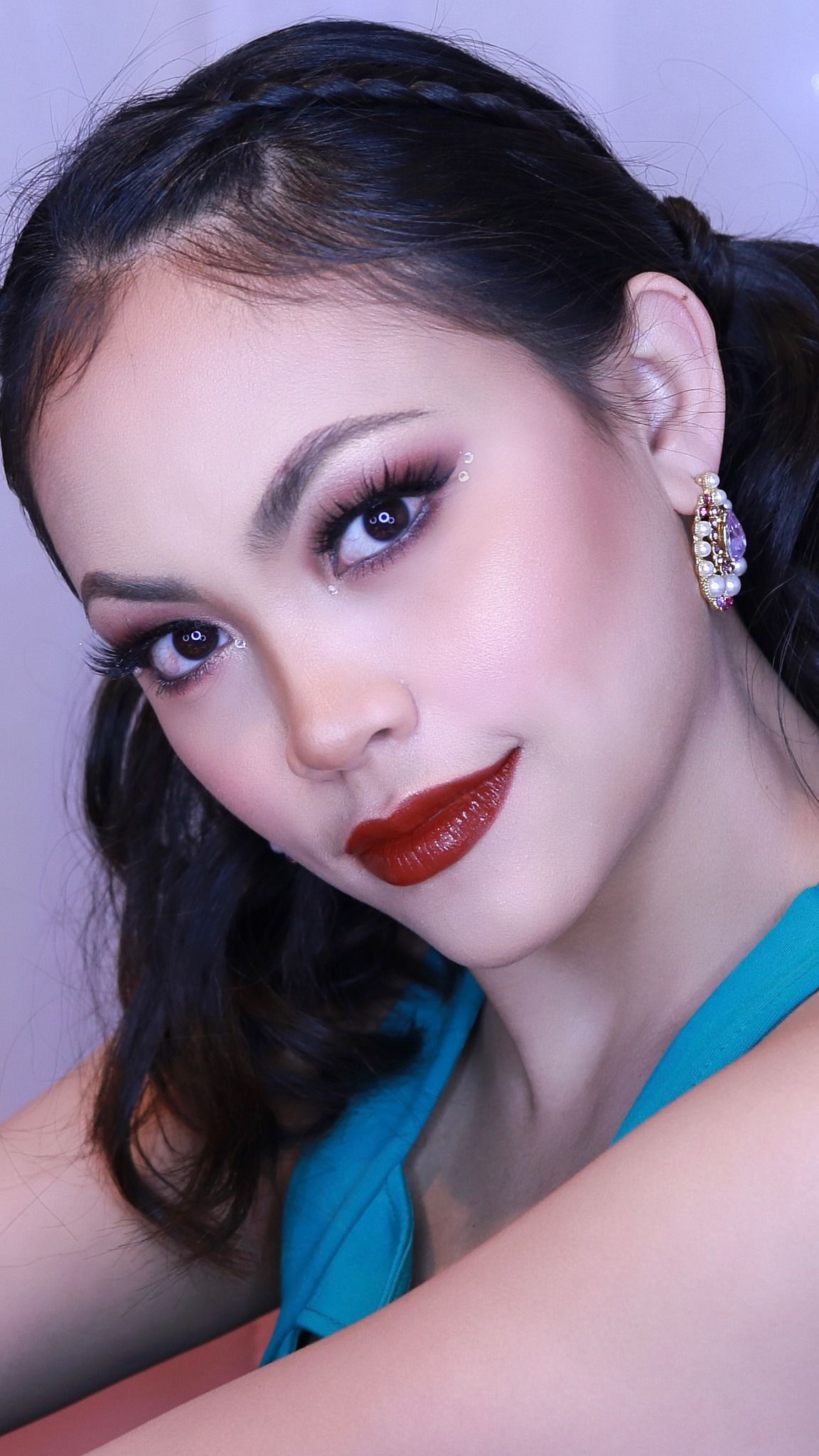 Glamorous makeup look featuring red lipstick, smokey eyes and sparkly earrings.
