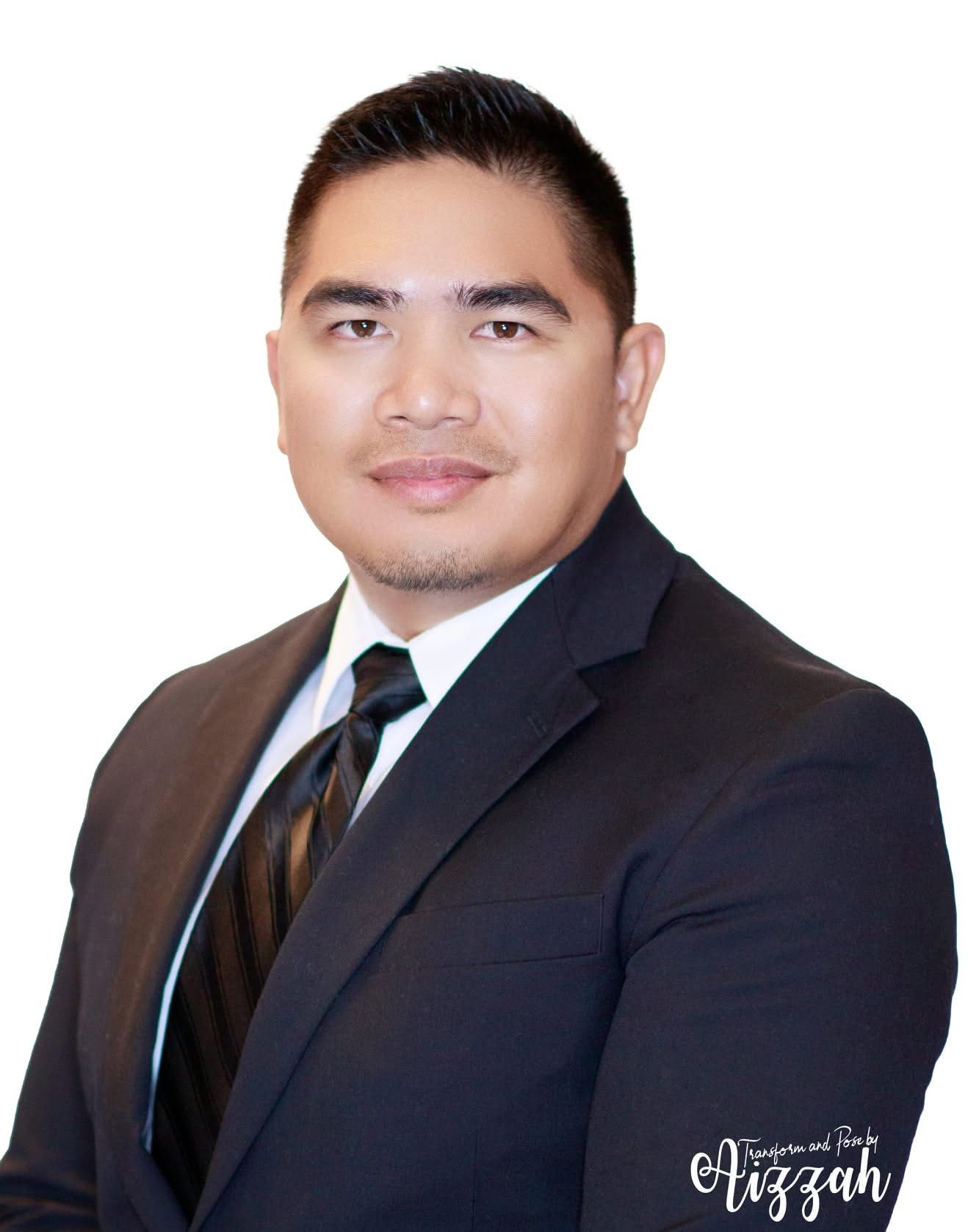 Professional headshot of businessman wearing dark suit and tie against light background.