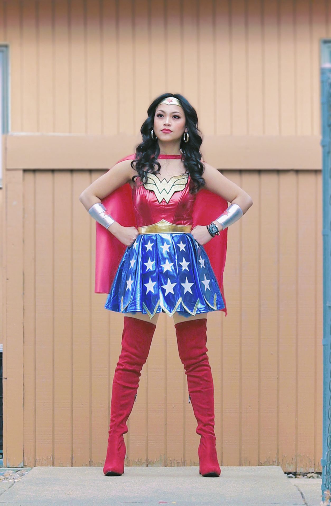 Wonder Woman costume cosplay with red boots and star-spangled skirt against beige backdrop.