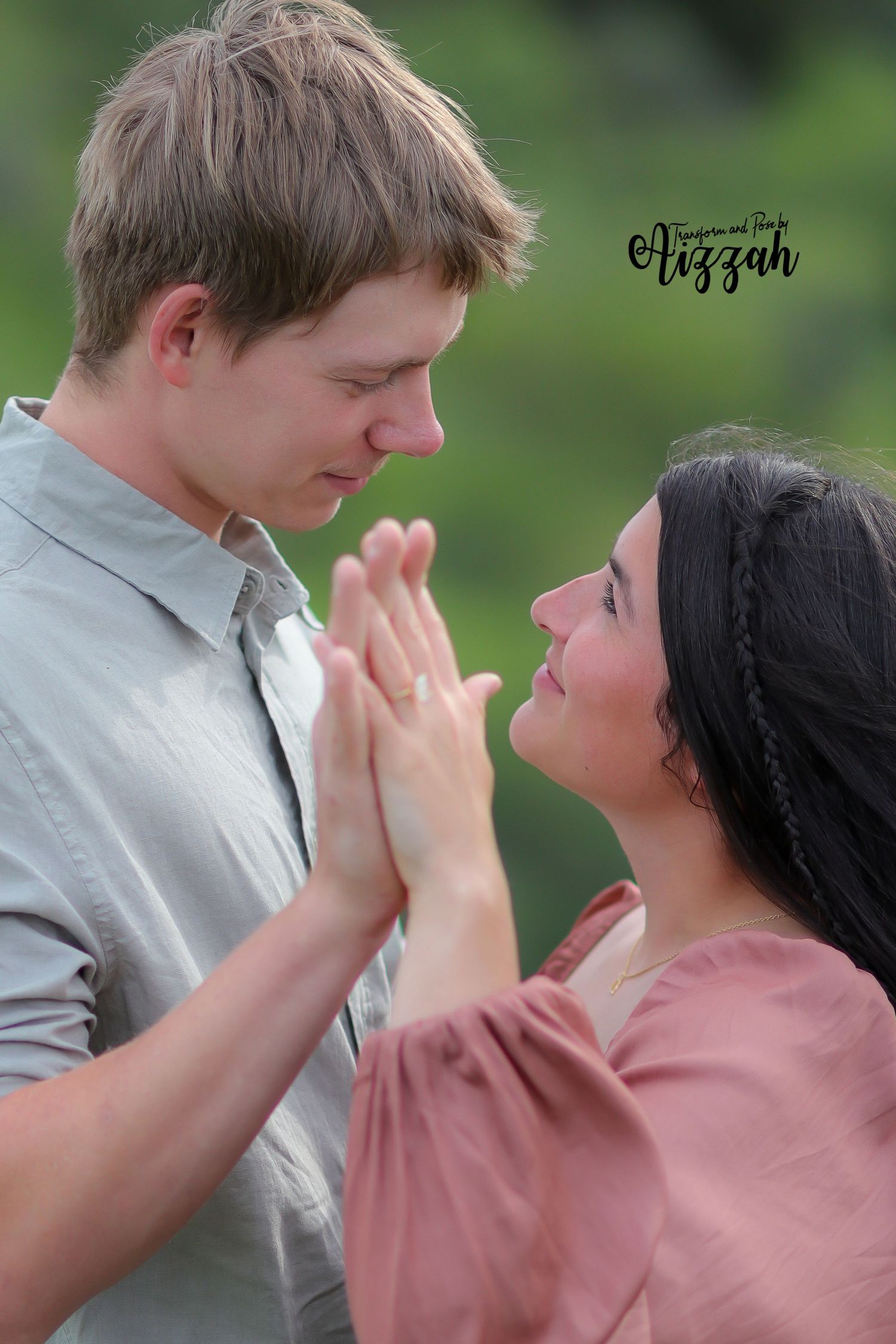 Couple shares tender moment during outdoor photoshoot in green setting.
