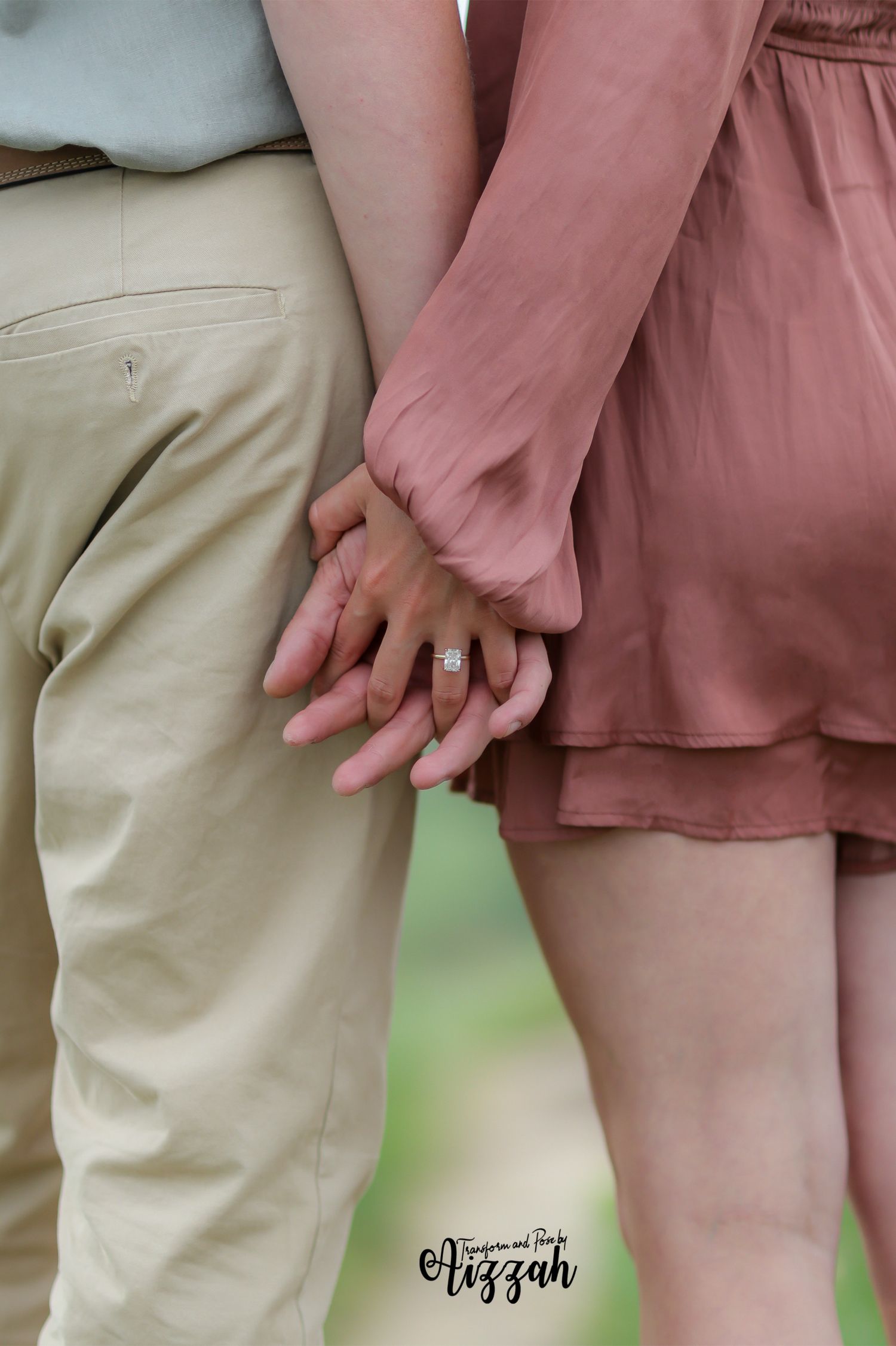 Close-up shot of couple holding hands, wearing pink dress and khaki pants.