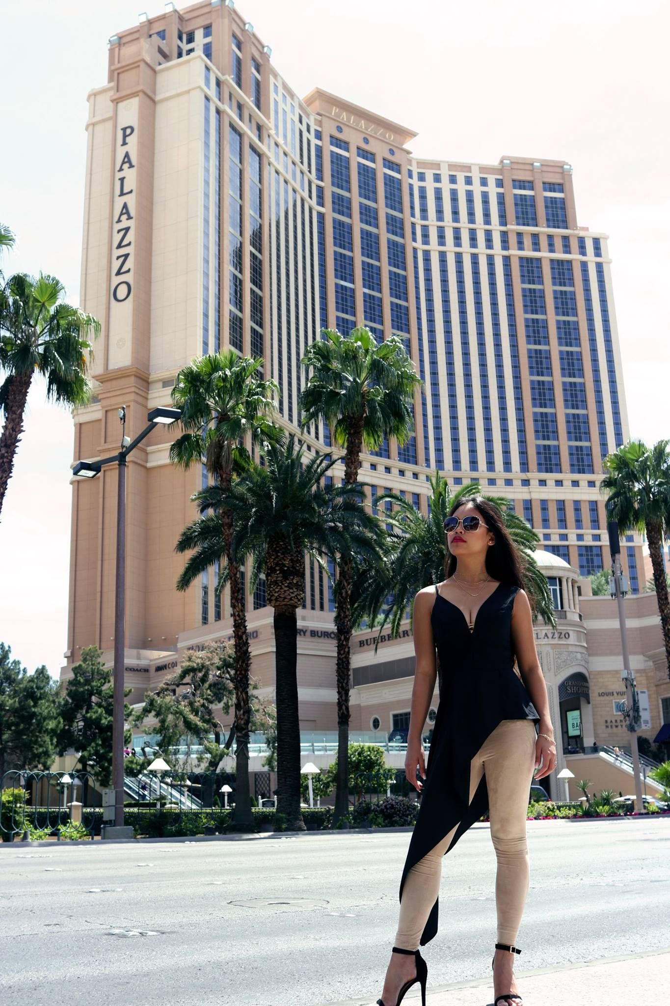 Stylish photo taken in front of the Palazzo hotel in Las Vegas with palm trees and architecture.