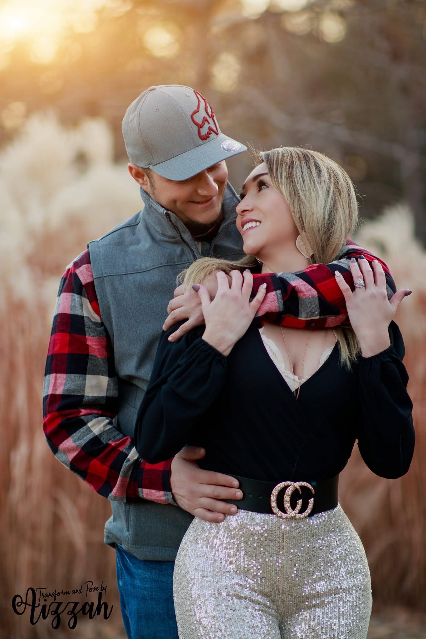 Couple embracing at sunset with woman in black top and man in plaid shirt.