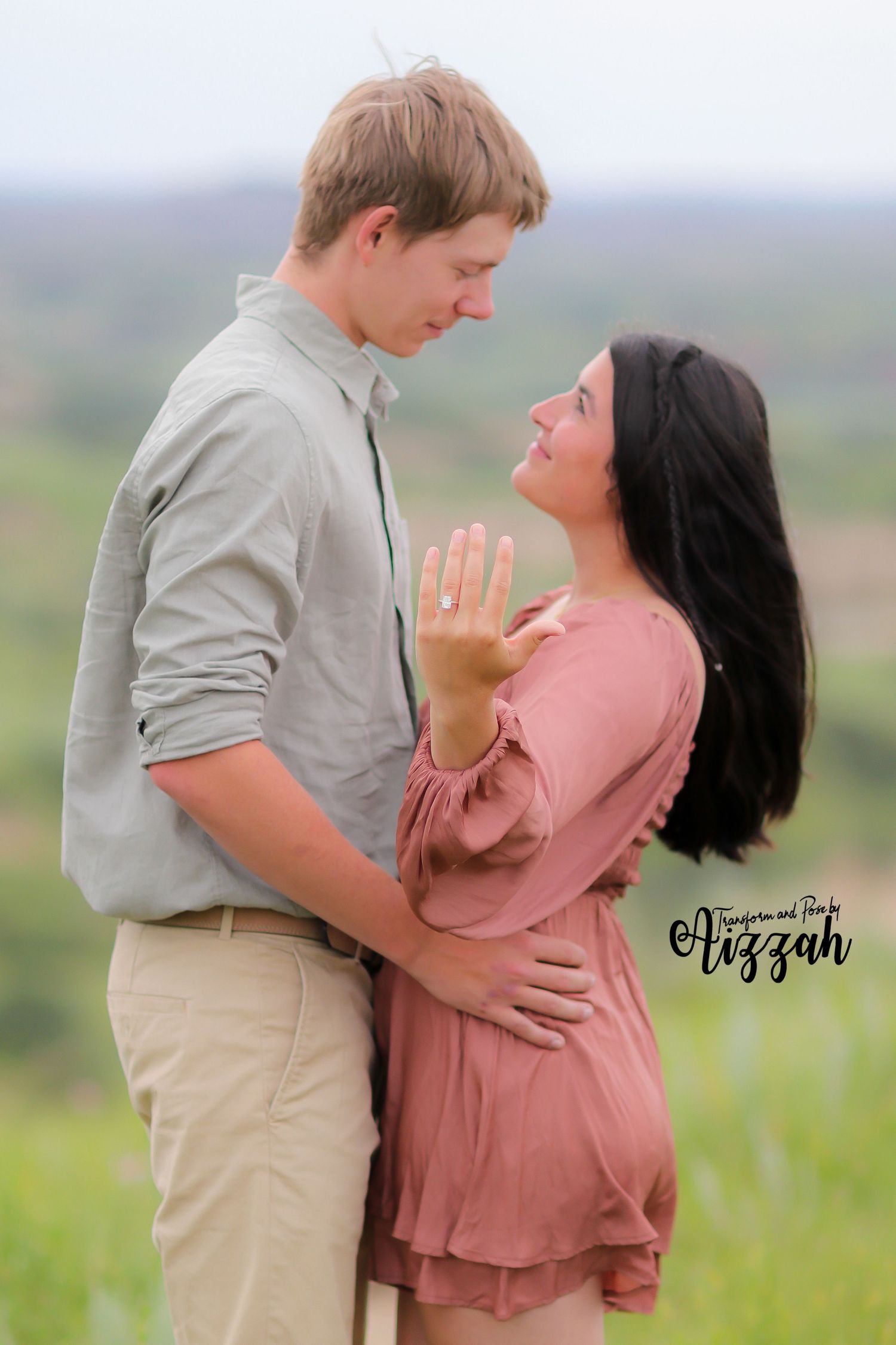 Couple embraces tenderly in an outdoor field during golden hour.