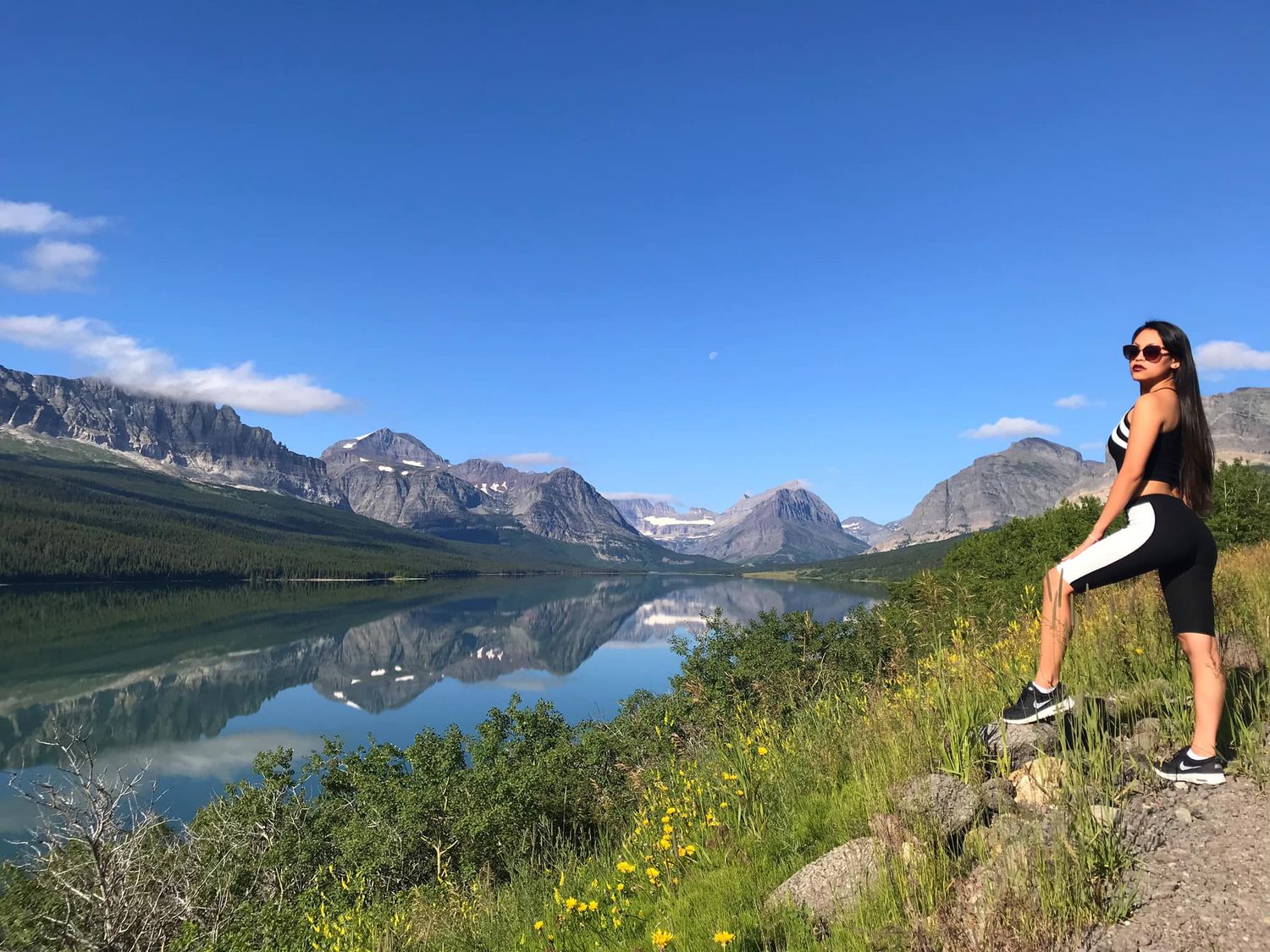 Hiker enjoying scenic mountain lake views in a national park with dramatic peaks reflecting in water.