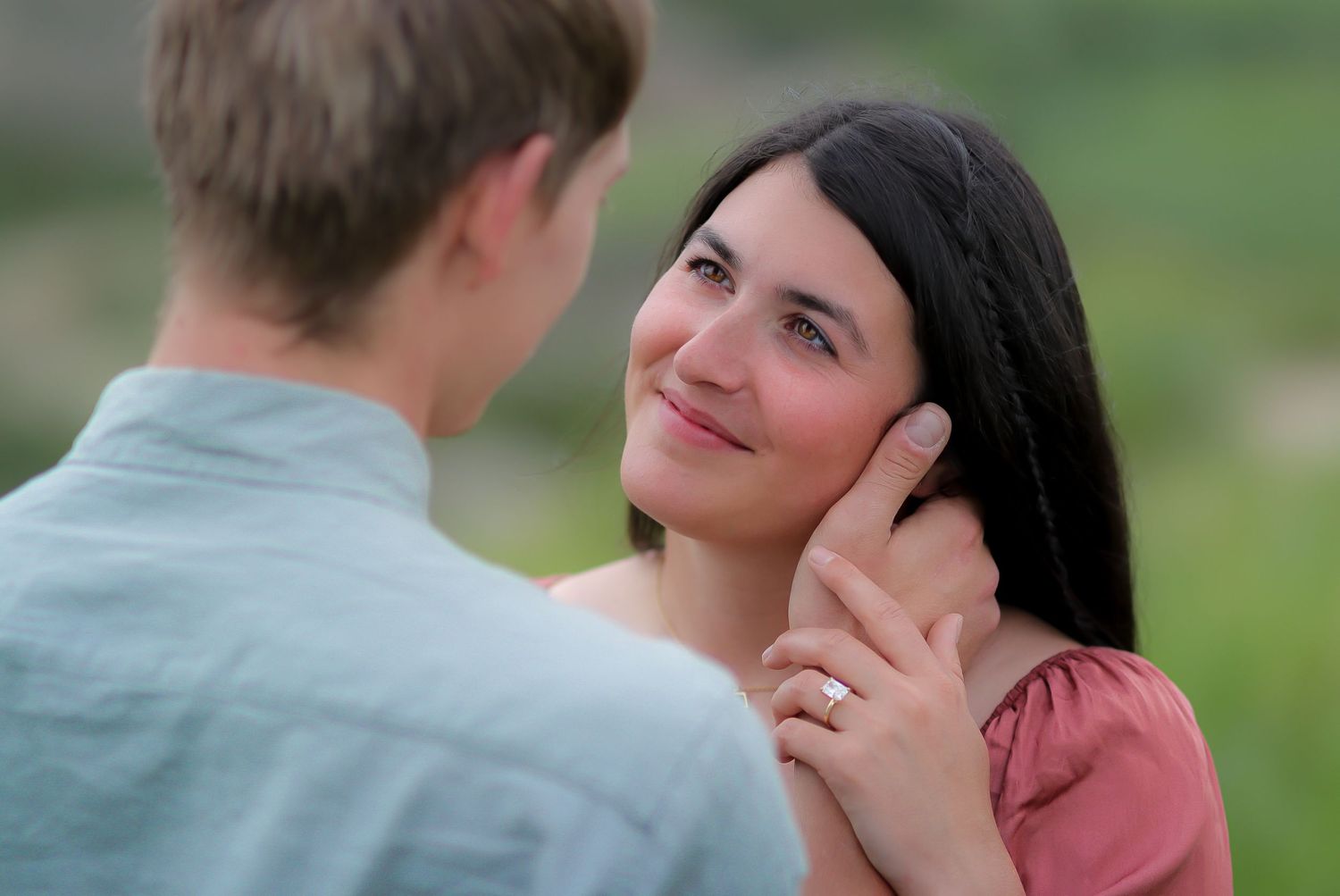 Intimate outdoor portrait series showing gentle interaction between two people against green background.