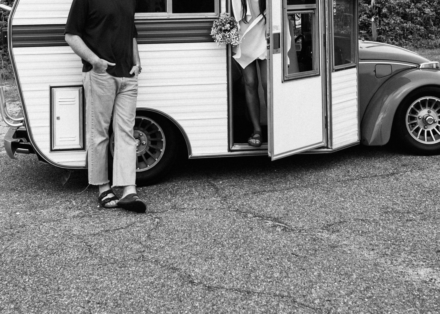Monochrome image showing partial view of people entering a classic camper van.