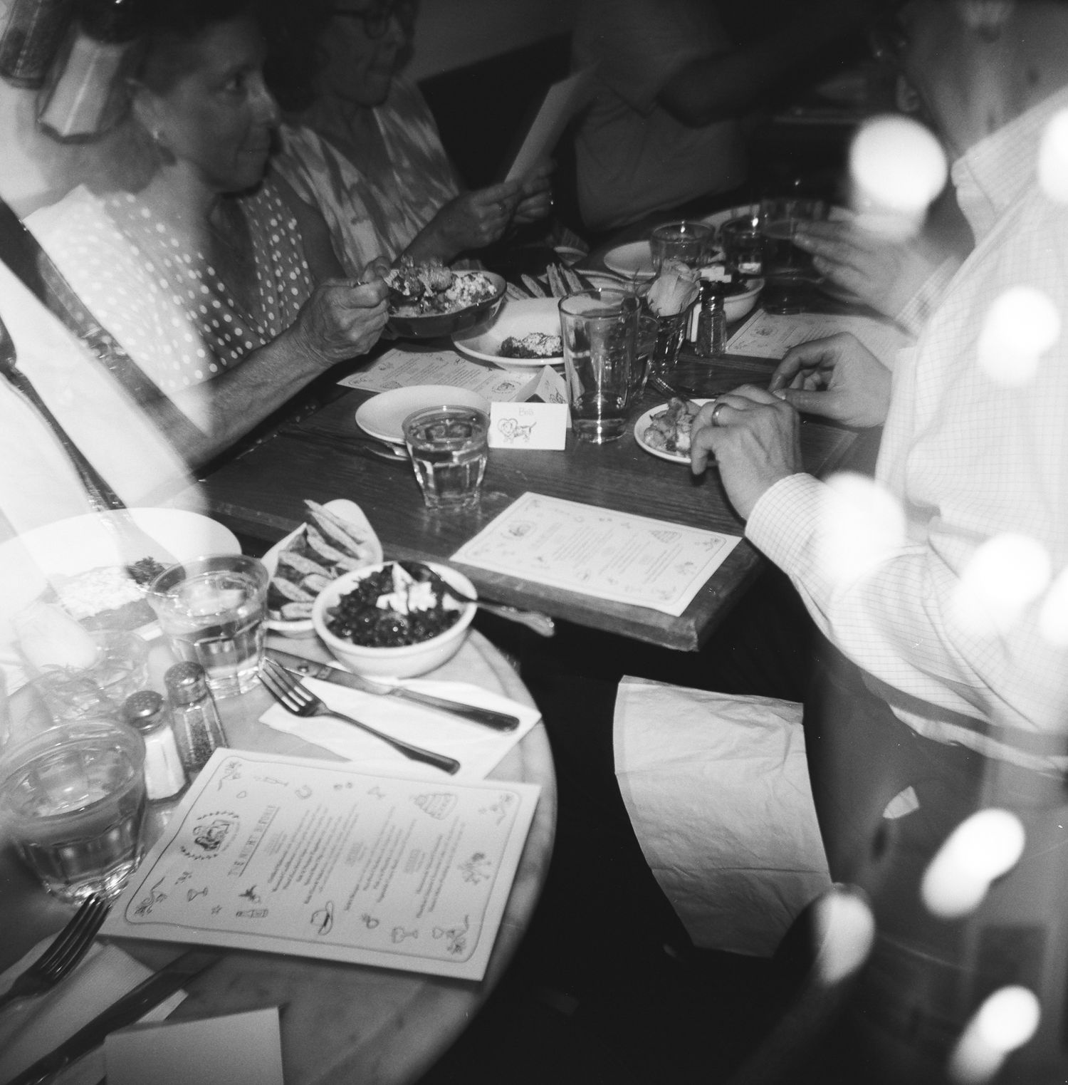 Diners looking at menus in a dimly lit restaurant setting, captured on 120 film with a Holga 120.
