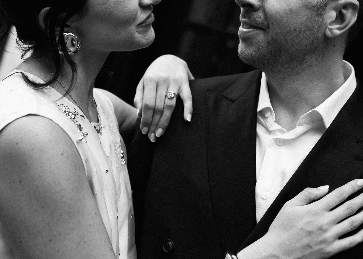A romantic black and white close-up moment between a couple in formal attire showing tender affection.