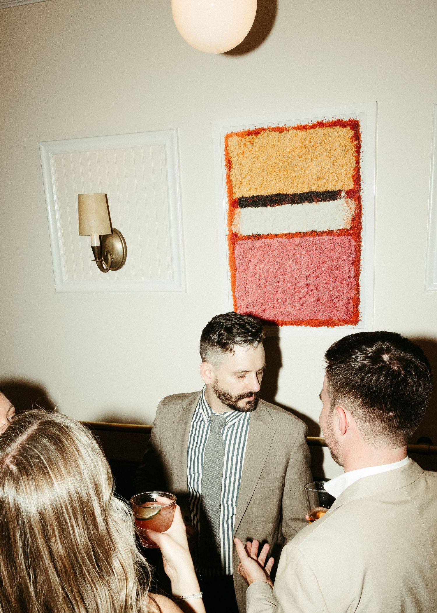 People socializing beneath a modern abstract painting and globe light fixture.