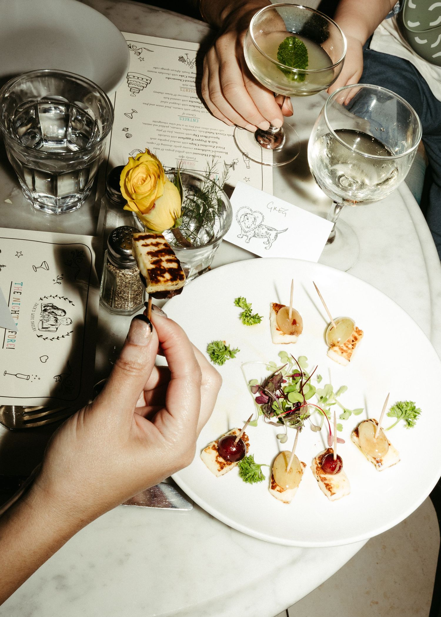 Overhead view of appetizer plates with cocktails and wine glasses on a restaurant table.