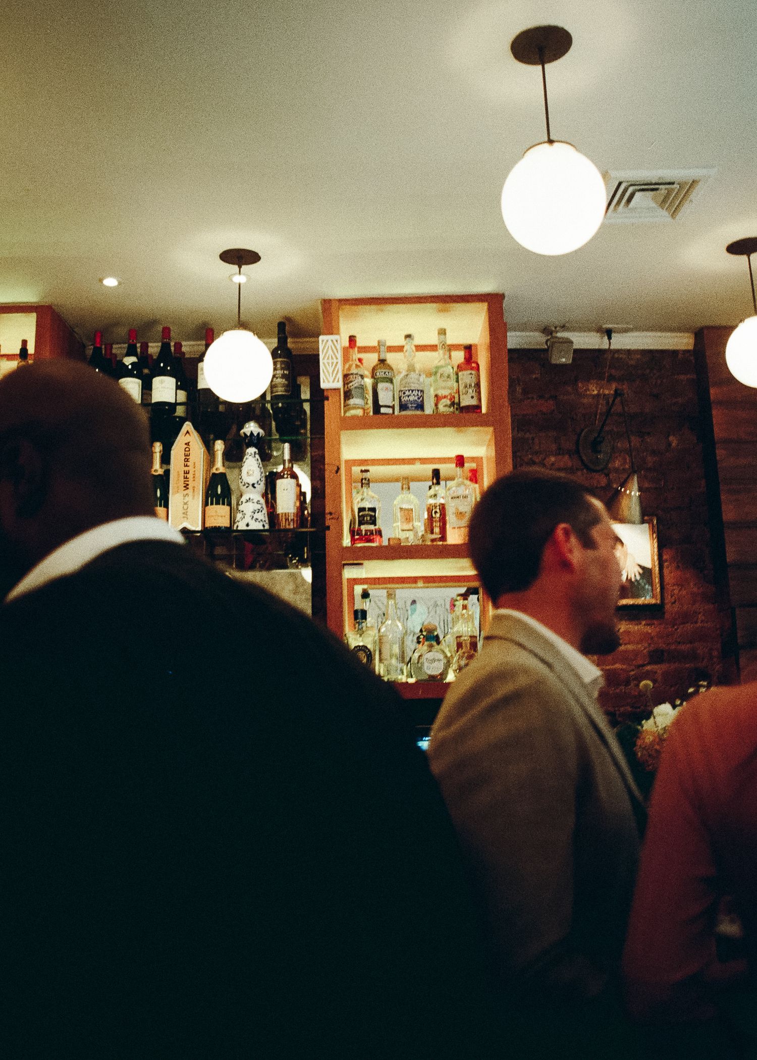 Interior of a cozy bar with globe pendant lights and shelves of liquor bottles, captured on 120 film with a Holga 120.