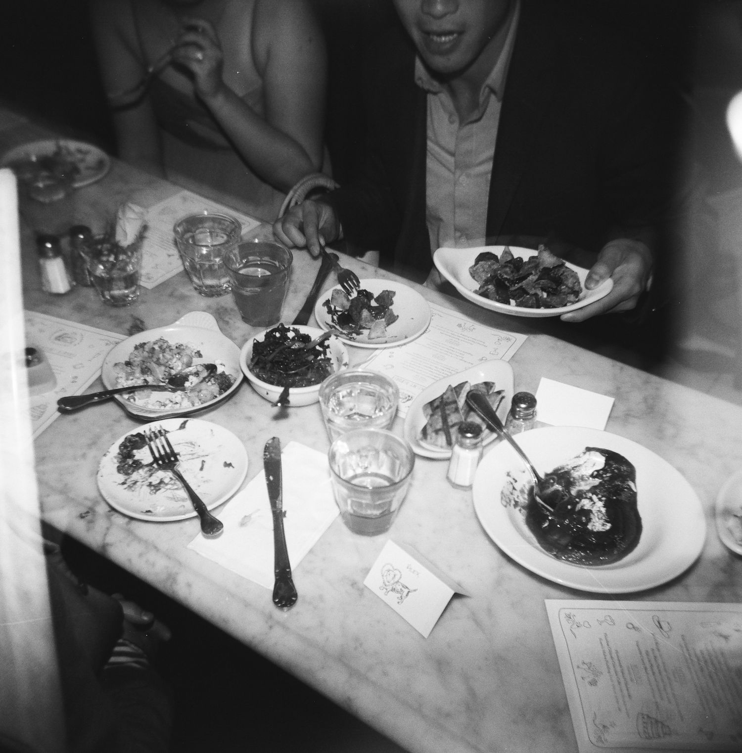 Overhead view of partially eaten meals and glasses on a restaurant table, captured on 120 film with a Holga 120.