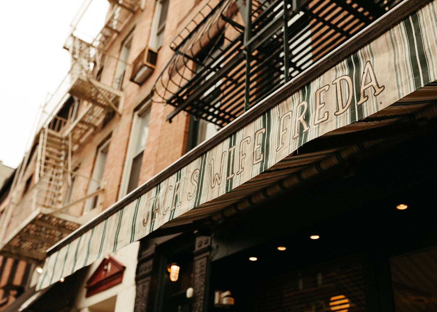Vintage New York City building exterior with fire escapes and classic storefront signage.