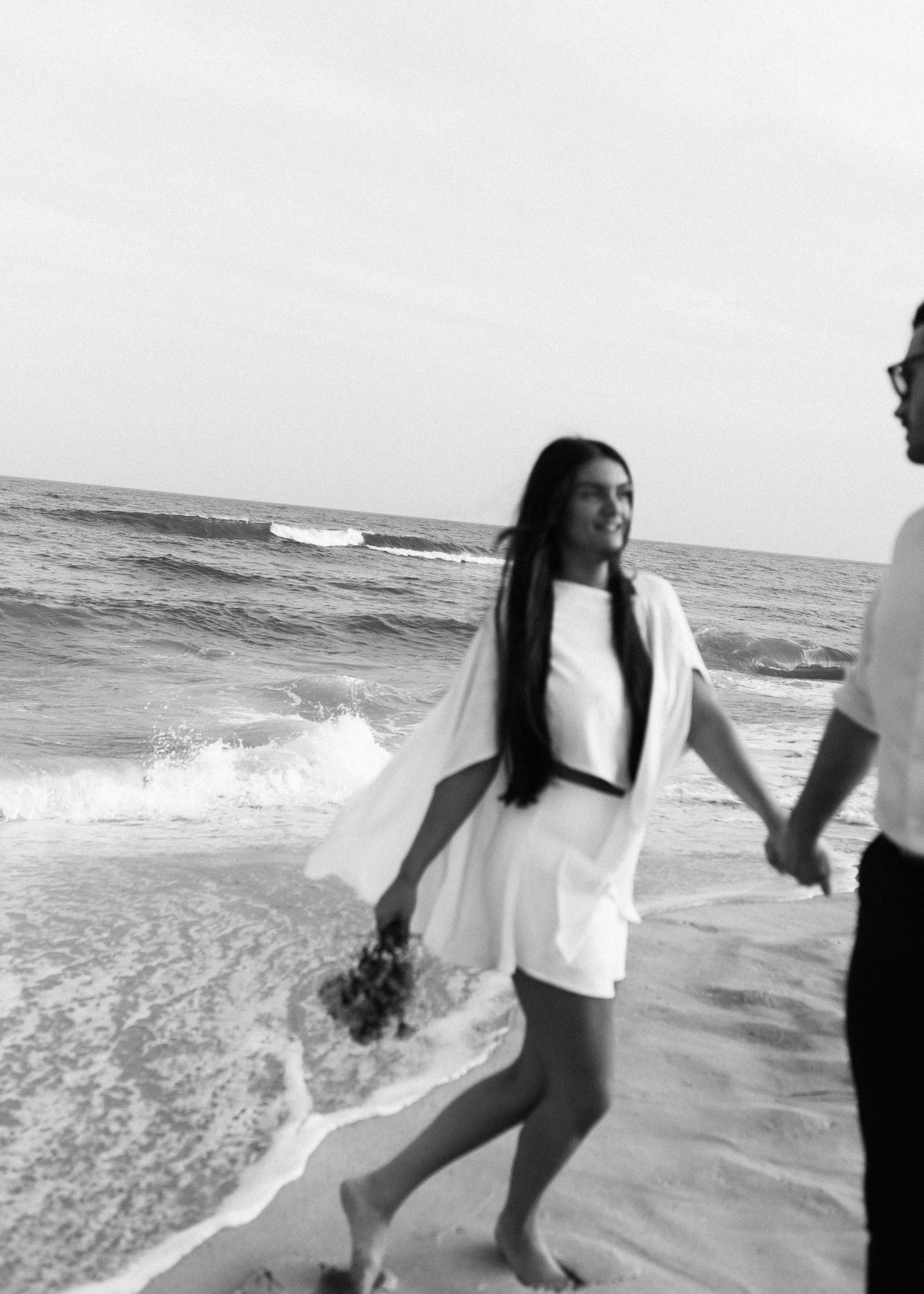 A romantic black and white beach scene with waves crashing in the background.