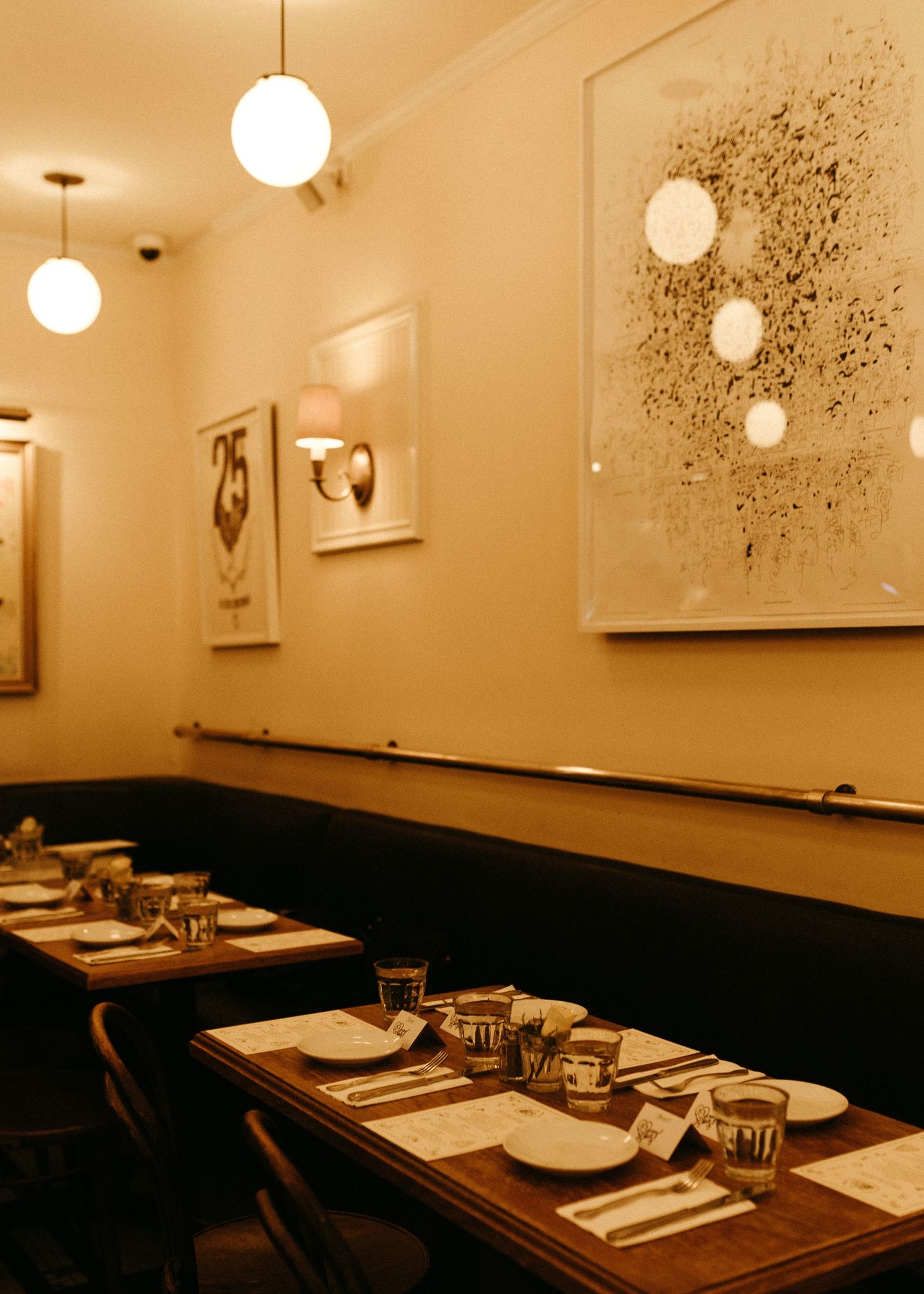 Upscale restaurant interior with modern globe pendant lights and booth seating set for dinner service.