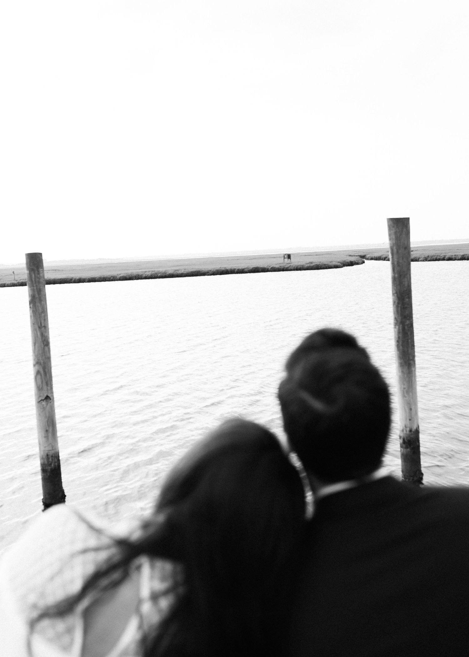 Silhouette of couple viewing the ocean from wooden pier at sunset.