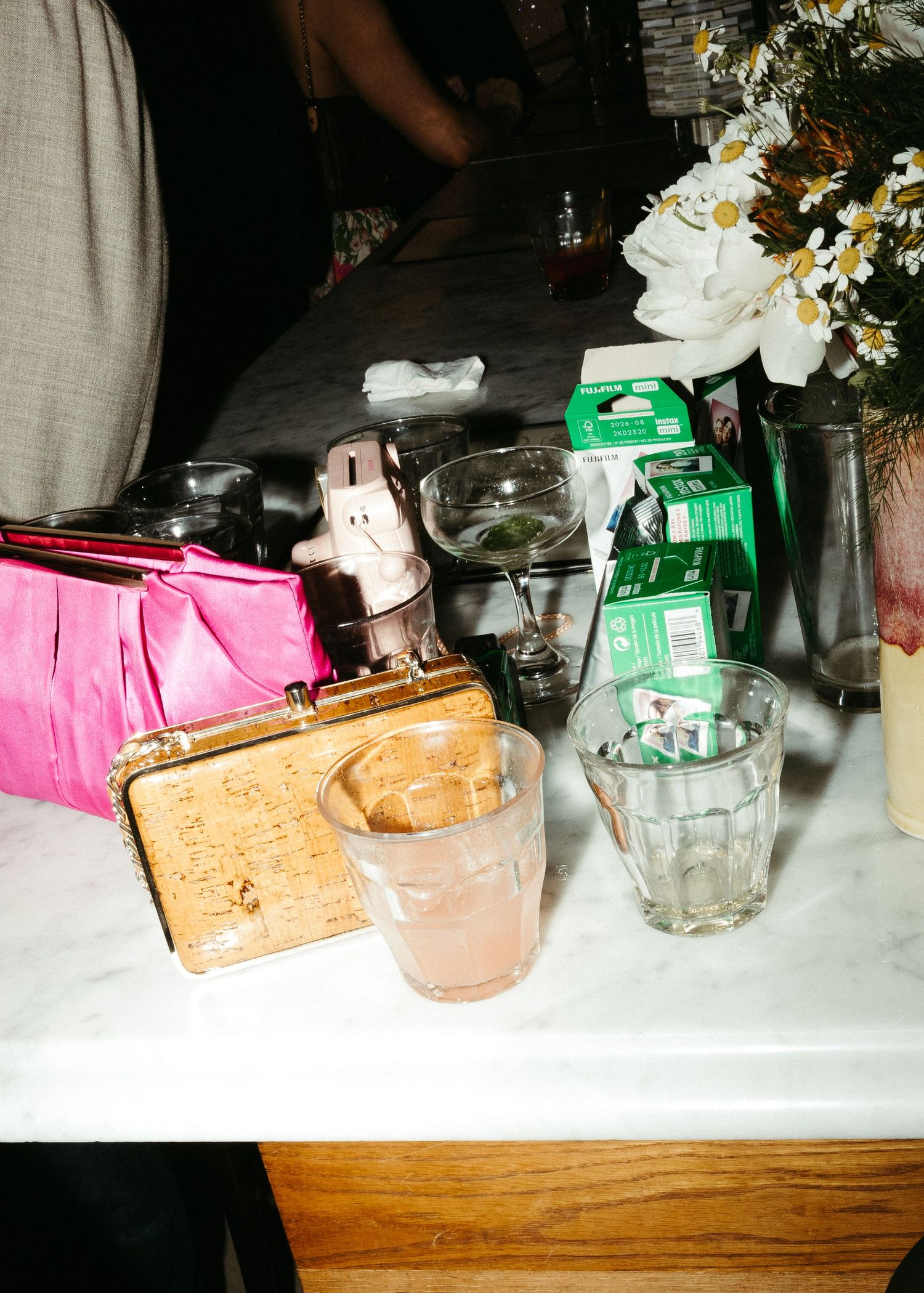 Colorful party favors, drinks, and floral arrangements on a marble surface at an event.