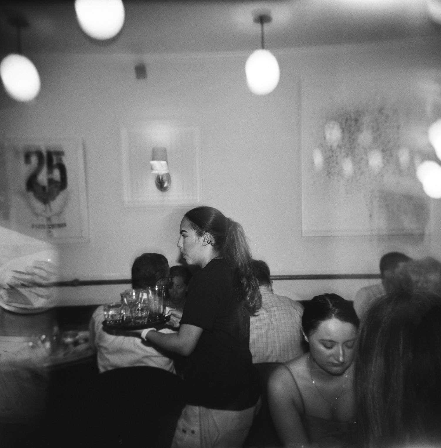 Restaurant staff serving customers in a busy dining room with pendant lighting, captured on 120 film with a Holga 120.