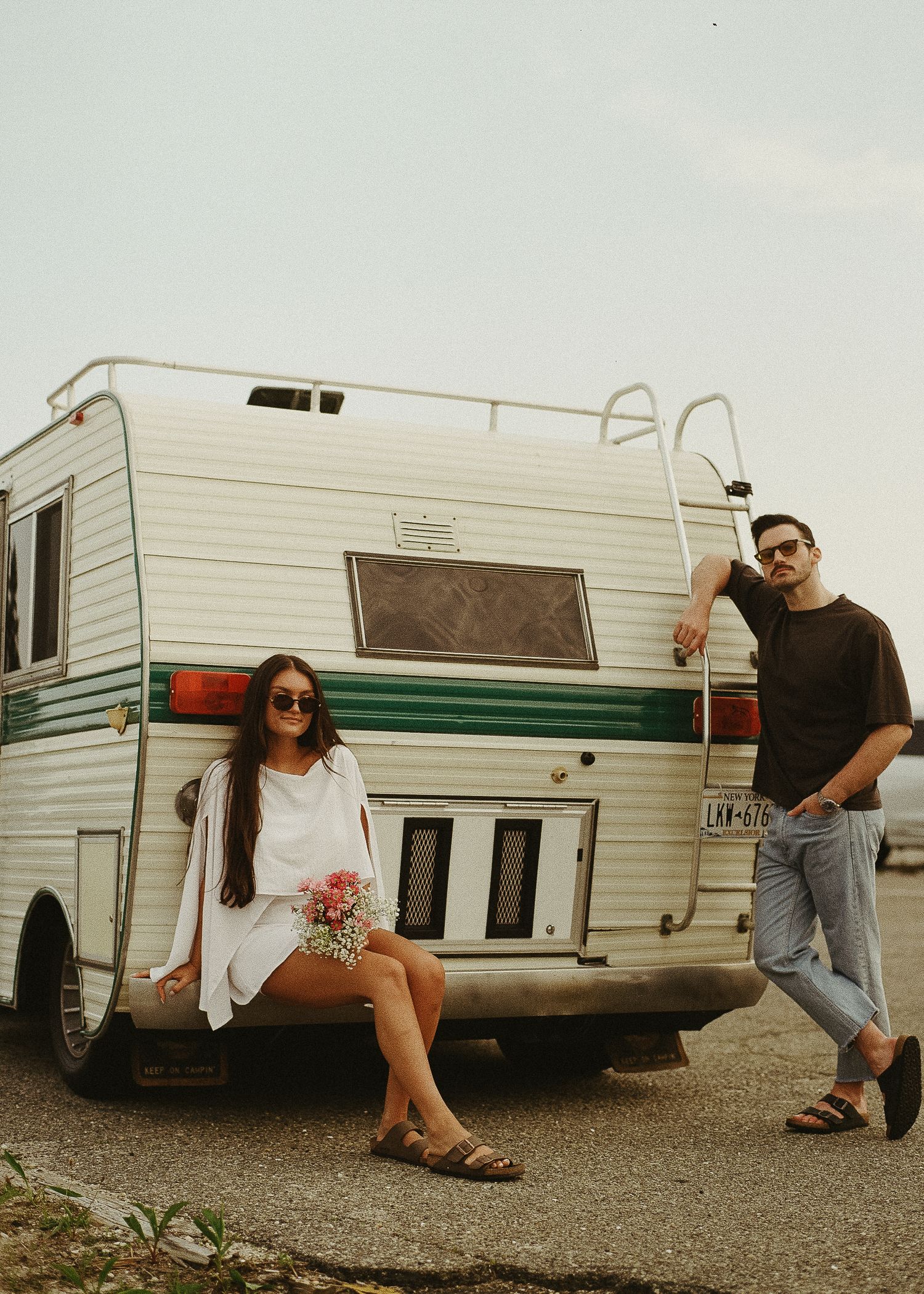 People interacting near a classic white and green striped retro camper trailer.