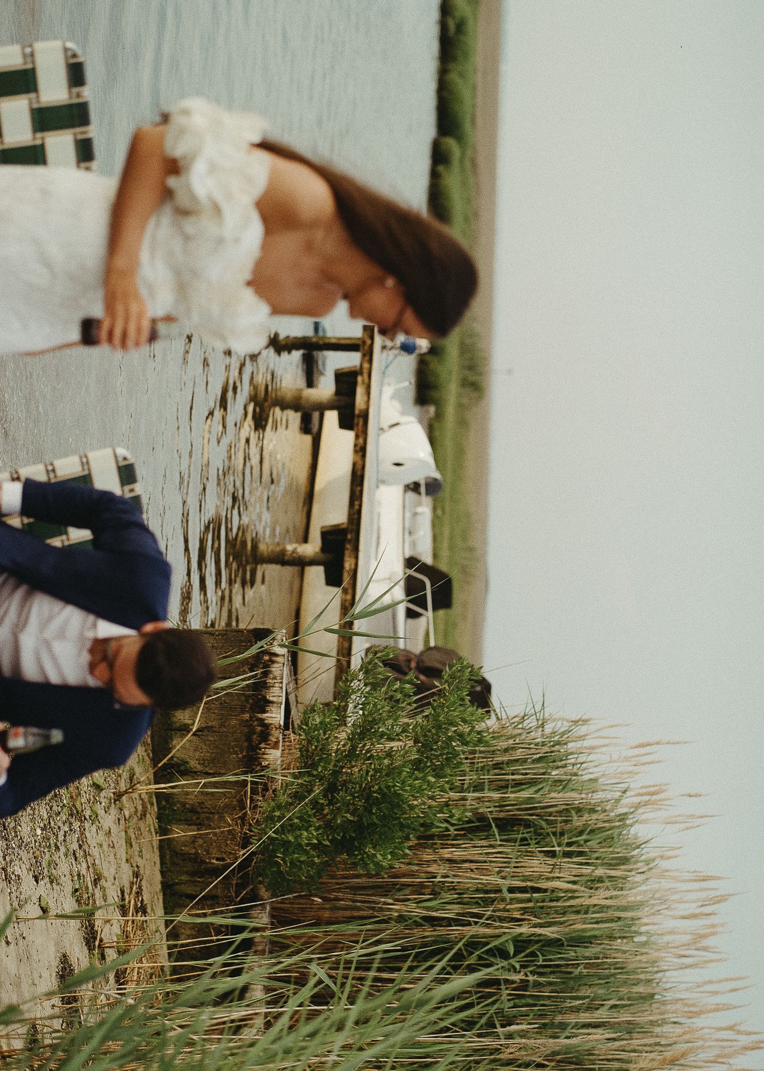 Coastal scene with marsh grasses and wooden dock pilings extending into calm water.