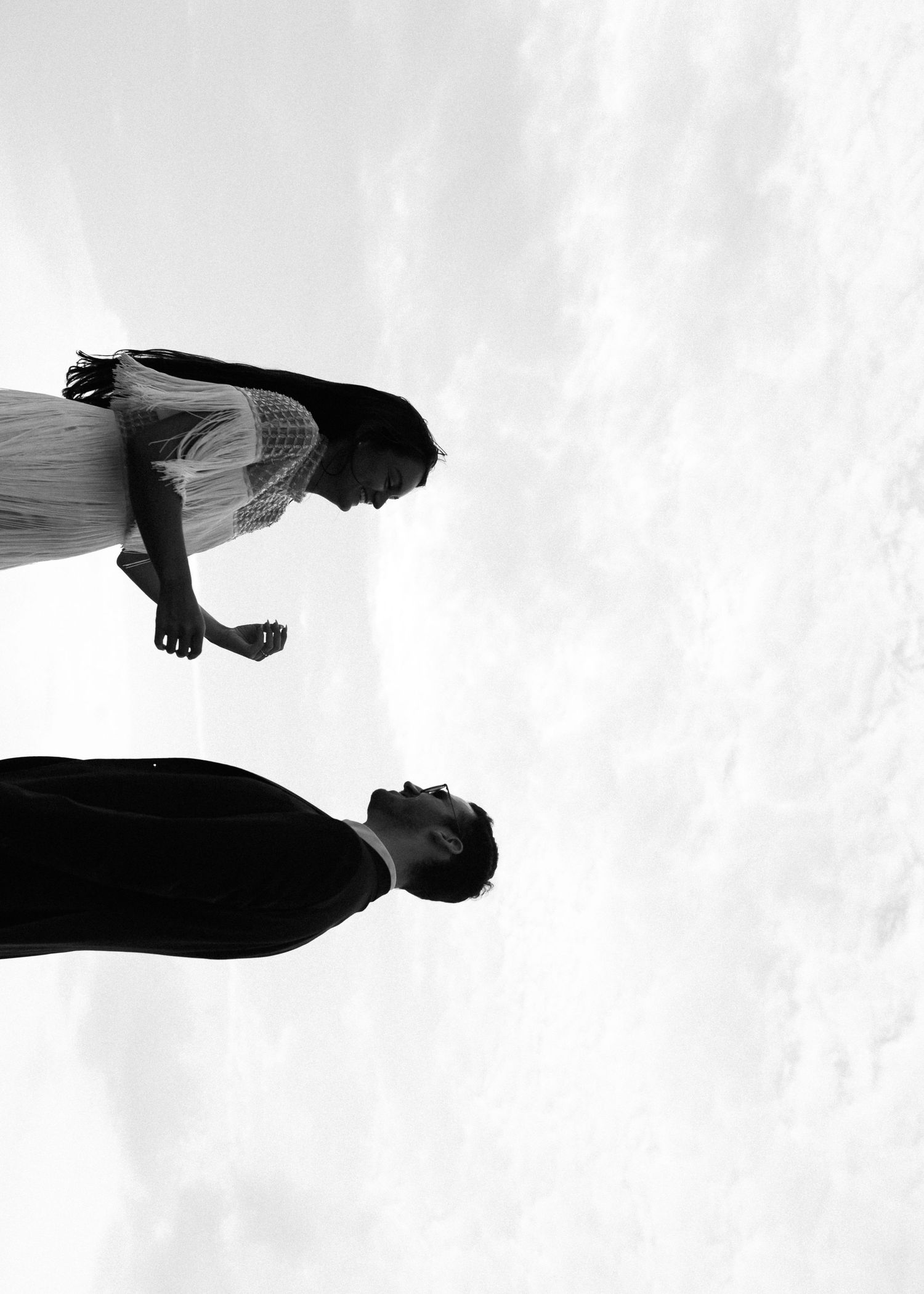 Artistic black and white silhouette of a couple against bright sky background.