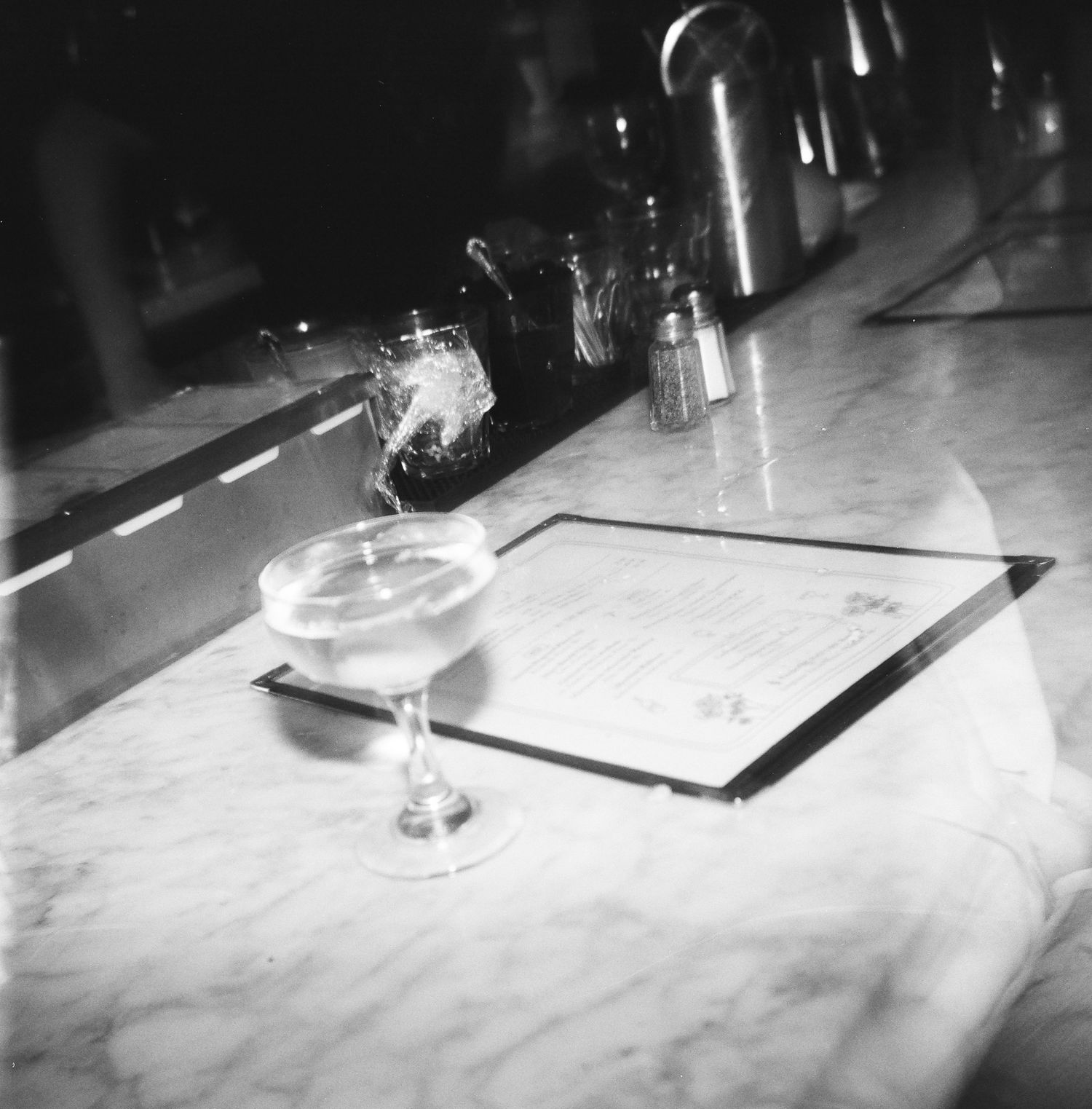 Menu and wine glass on a bar counter in monochrome, captured on 120 film with a Holga 120.