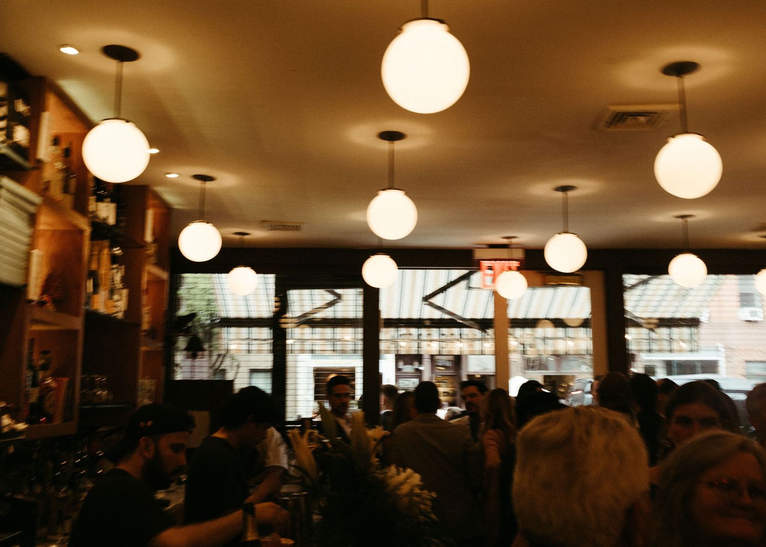 A crowded restaurant interior with hanging globe lights and warm ambient lighting.