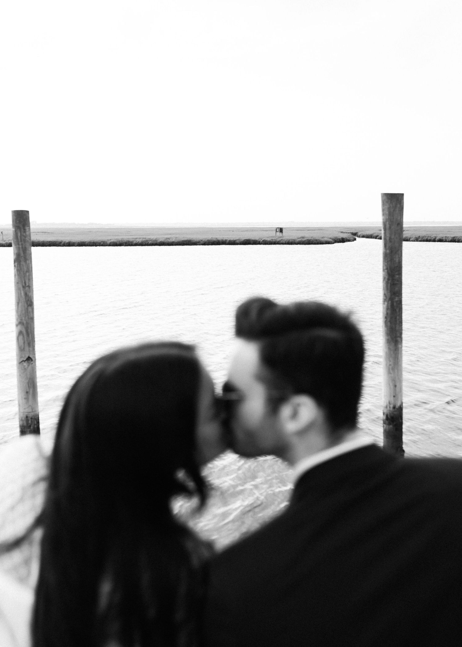 Romantic black and white moment captured on a pier overlooking the water.