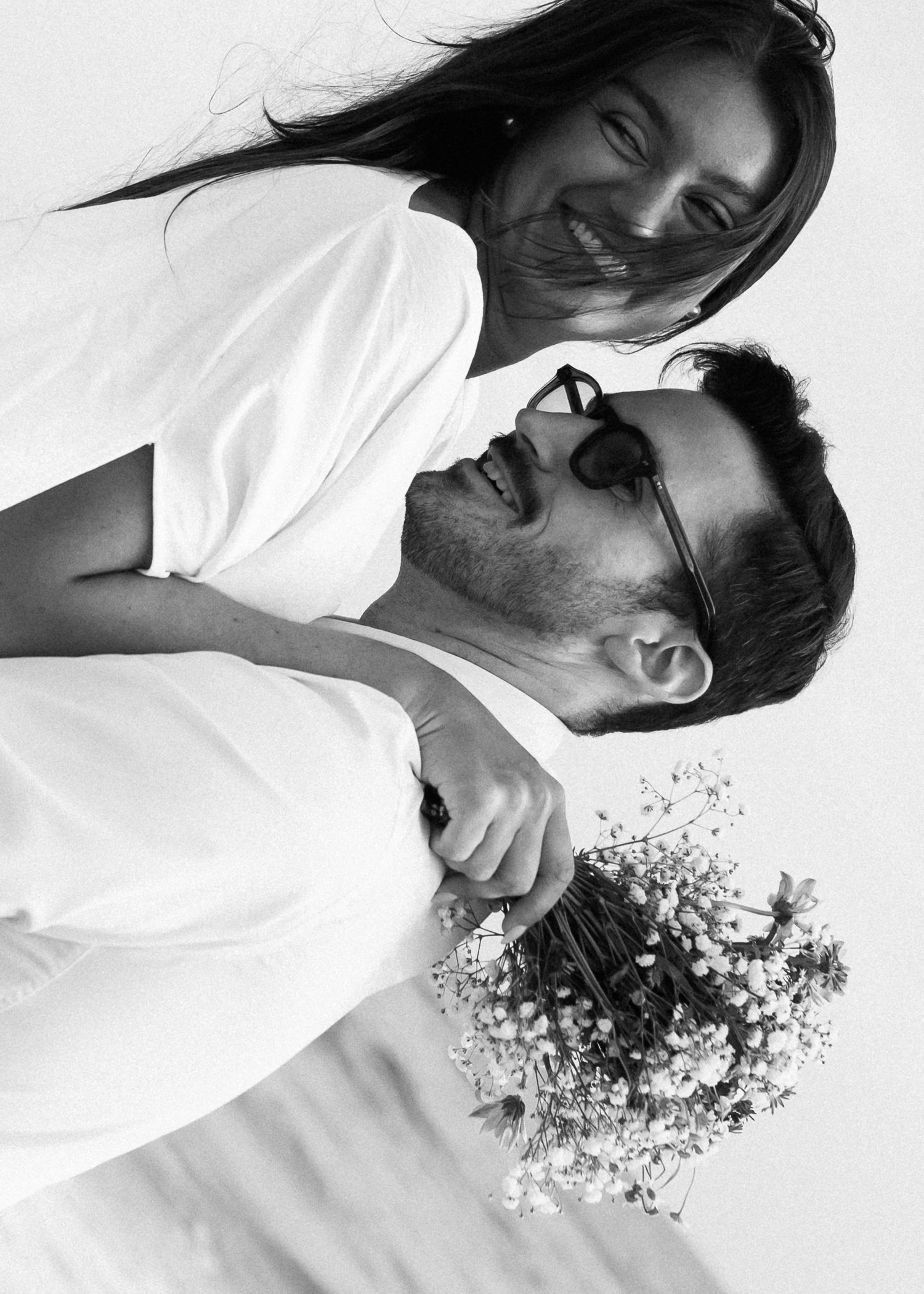 A close-up black and white portrait of a couple with a bouquet of flowers.