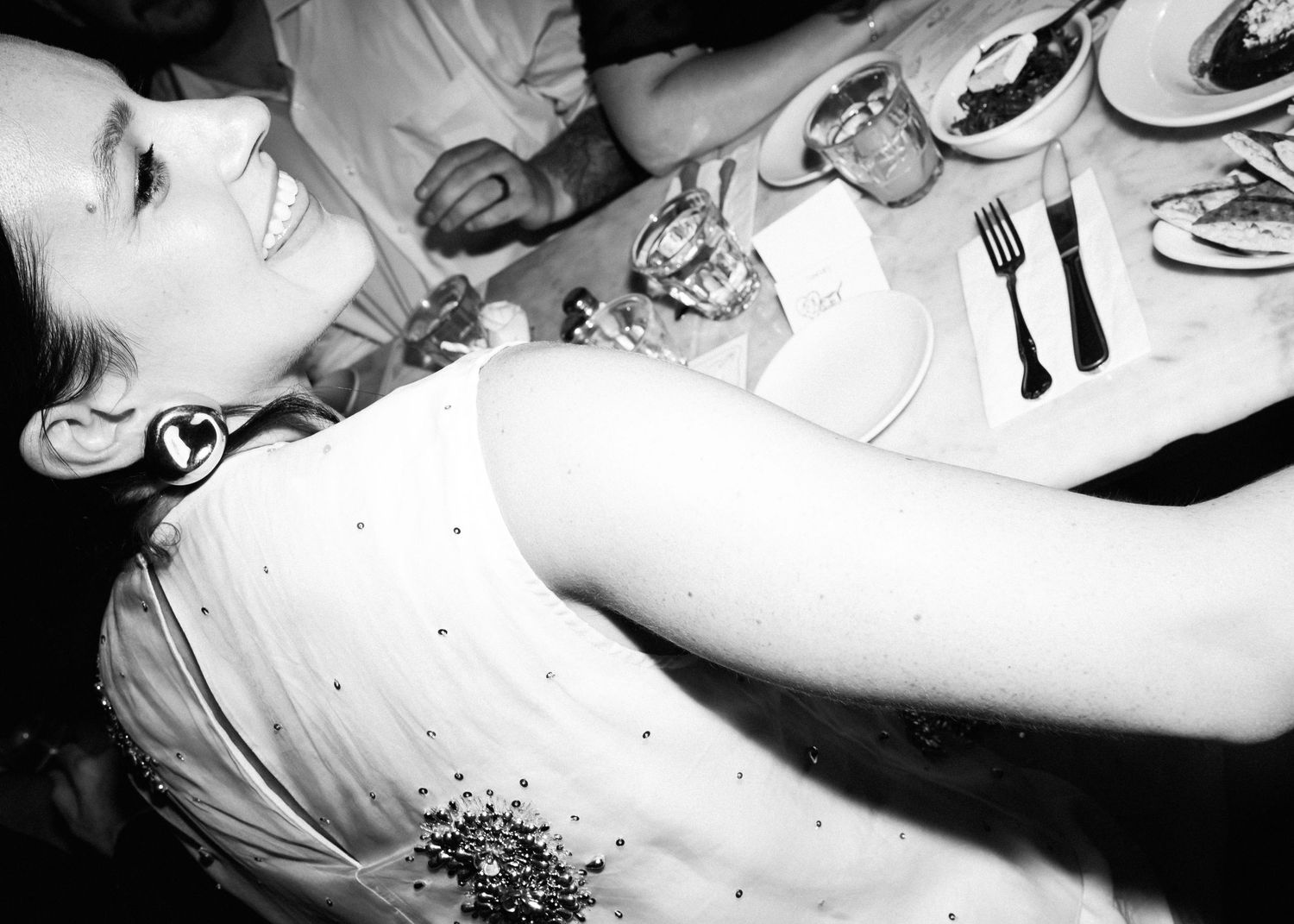 Black and white candid photo of dinner party guests at a formal event.