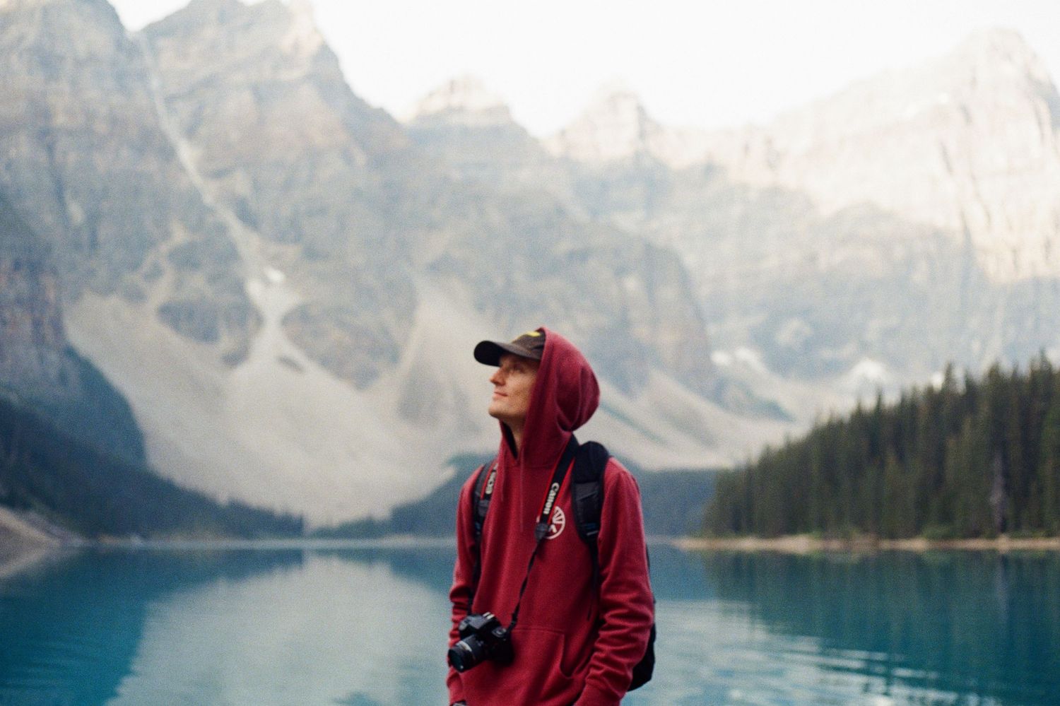 A photographer in a red jacket captures the scenic beauty of Moraine Lake in Banff National Park, Canada.
