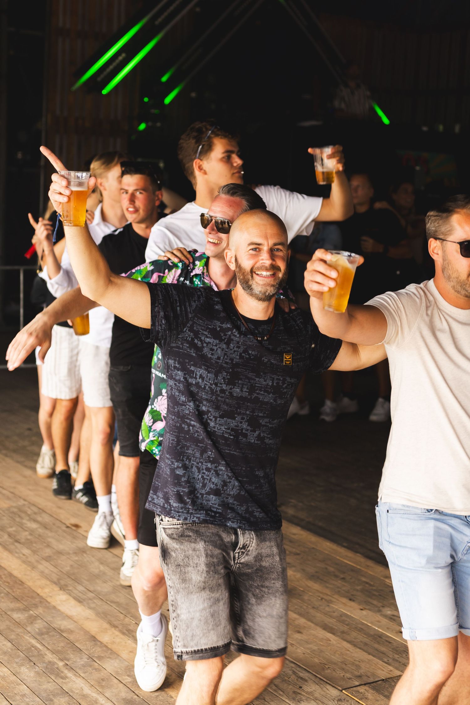 Group of people dancing and celebrating at a party with green laser lights.