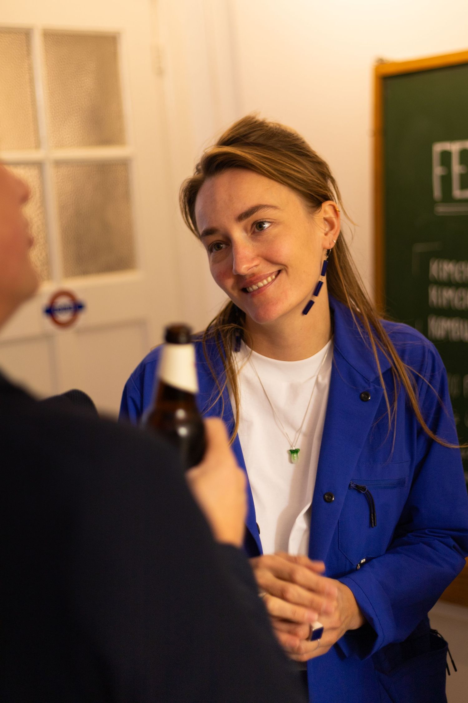 People engage in conversation during a beverage tasting event in a well-lit room.