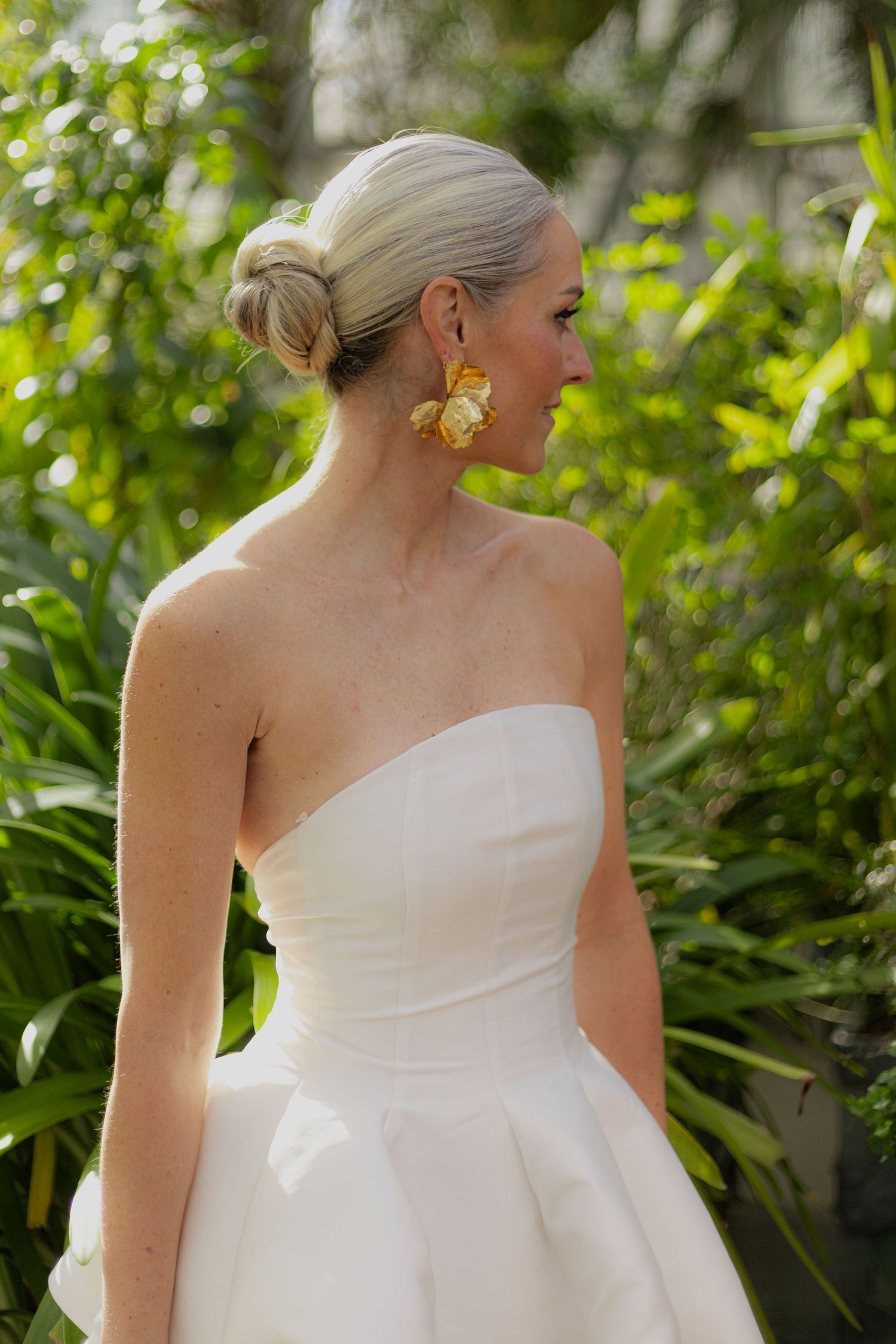 Elegant strapless wedding gown with architectural bodice details in an outdoor setting.